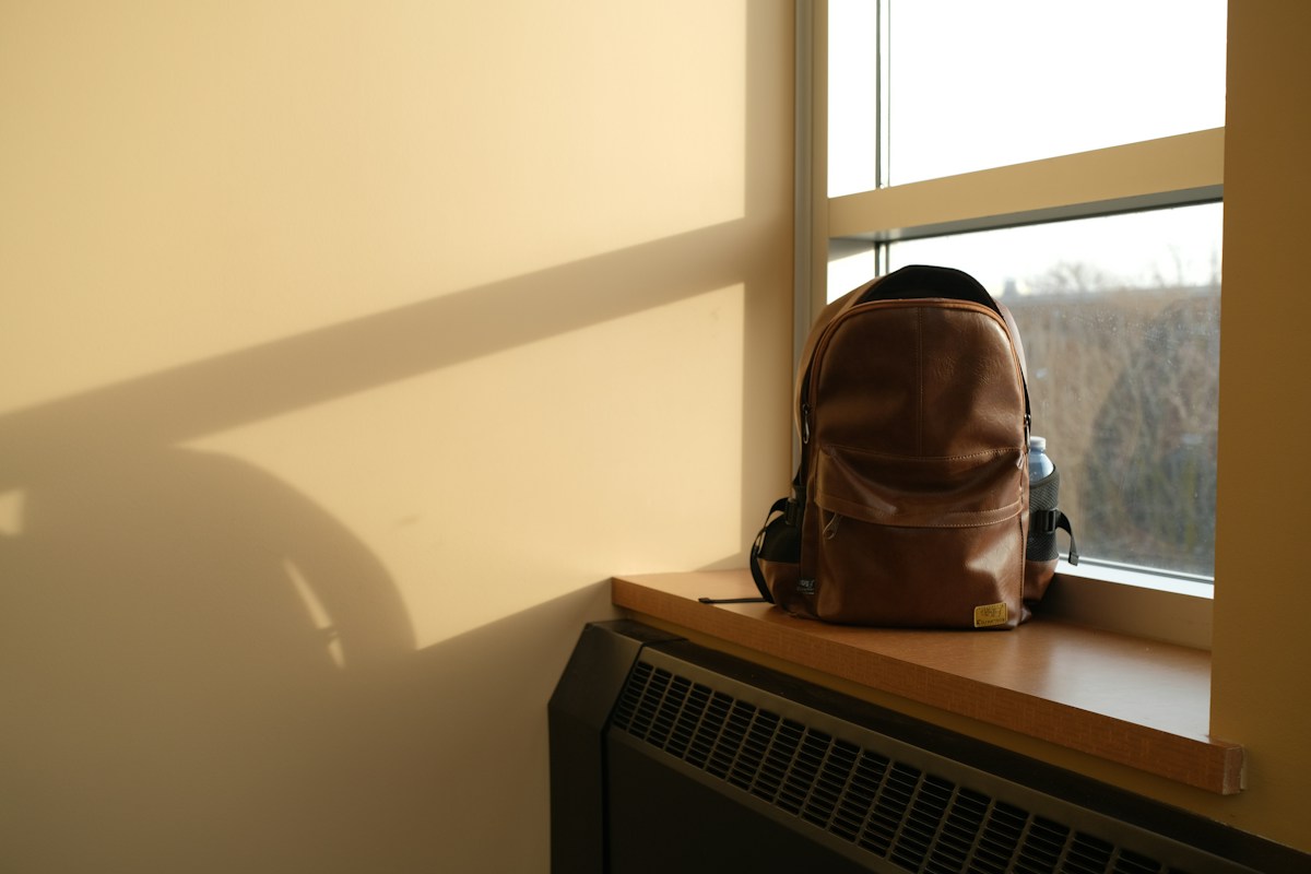 A backpack on a sunny window sill, symbolizing preparation for a college campus visit.