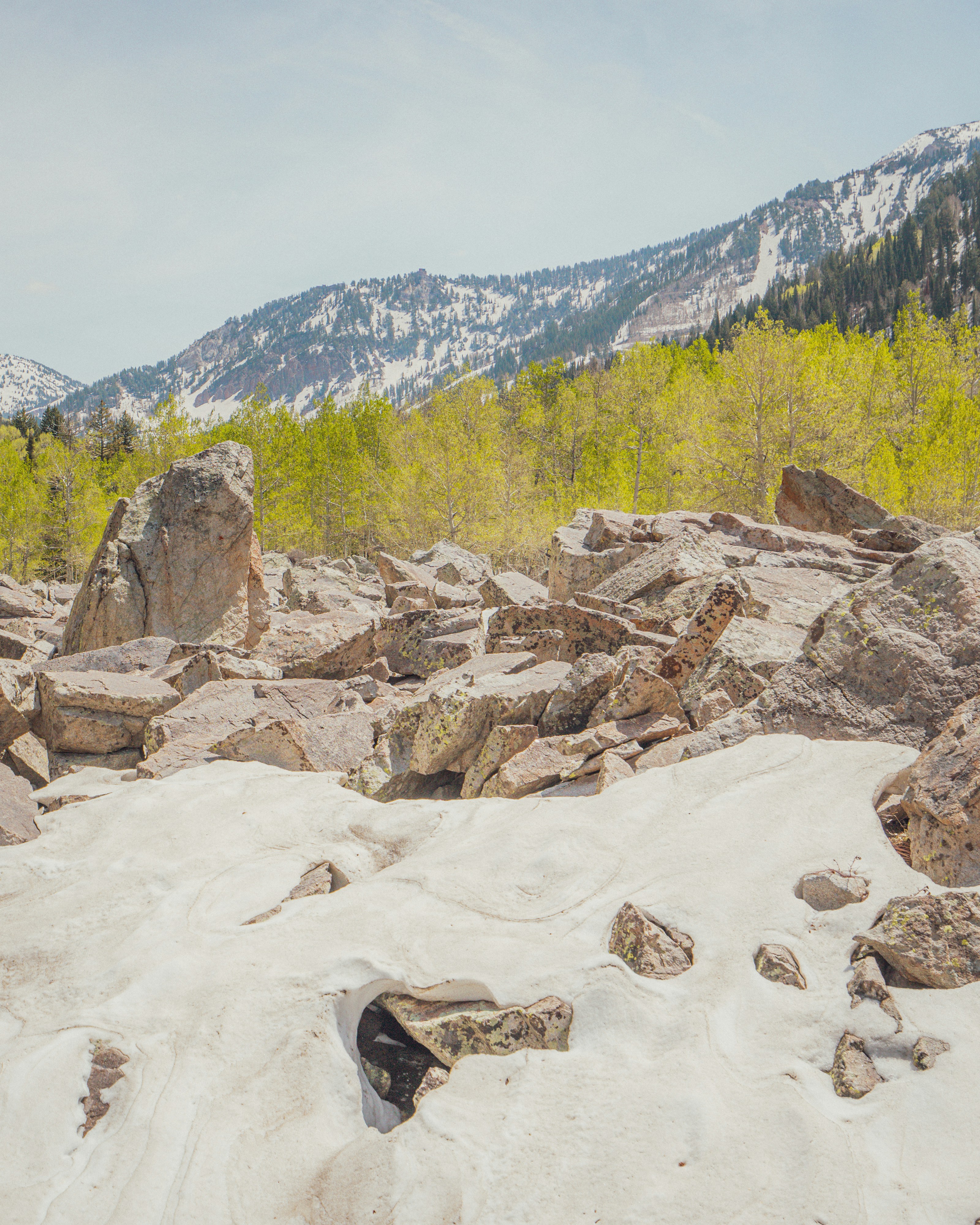 Rocky landscape with melting snow and a mountain backdrop.