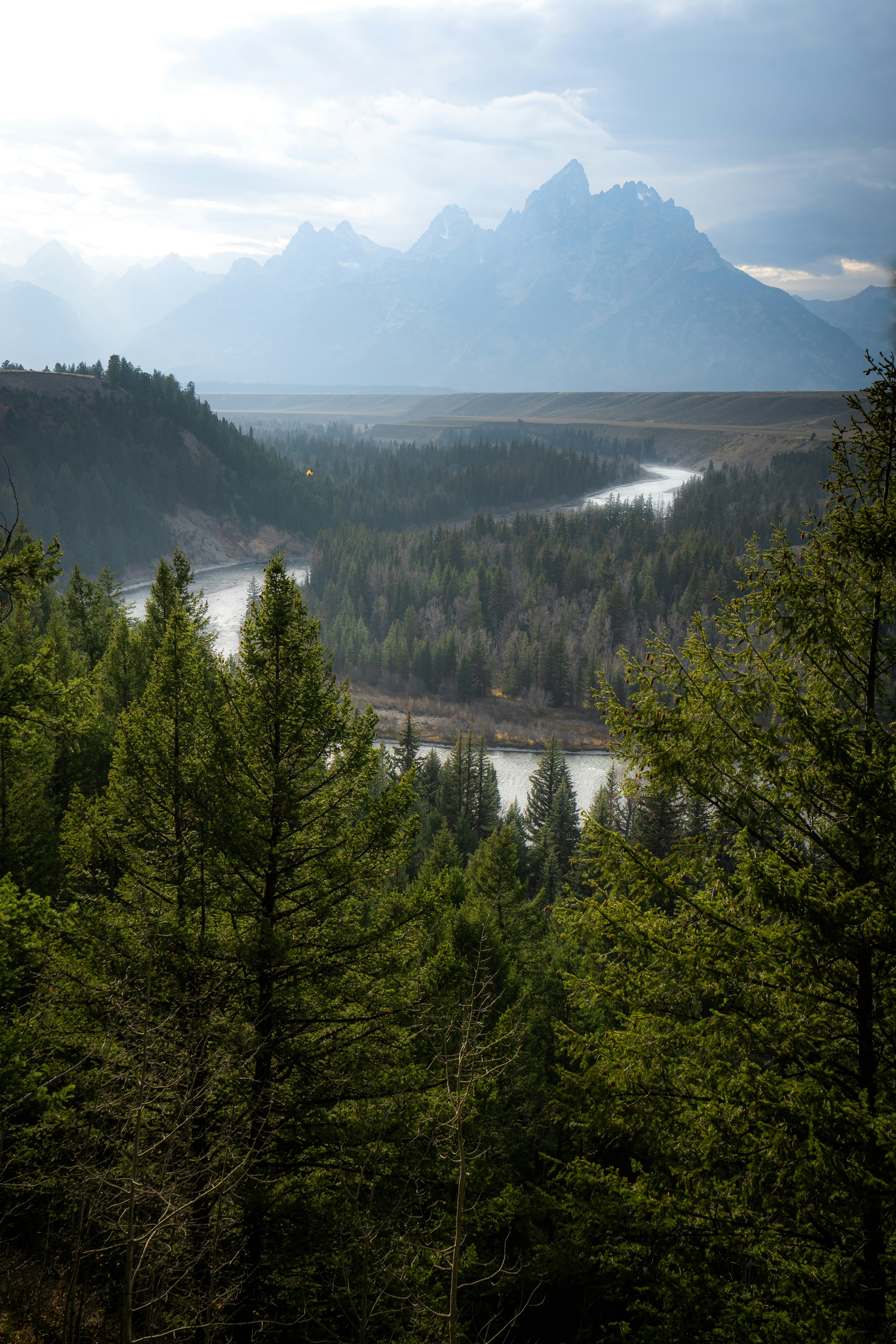 Mountains tower over a winding river and forests.