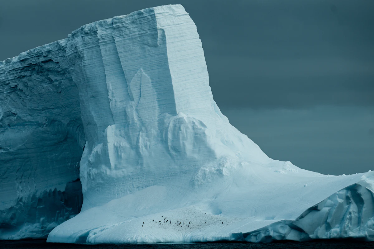 Massive tabular iceberg drifting across deep Antarctic waters under a moody sky