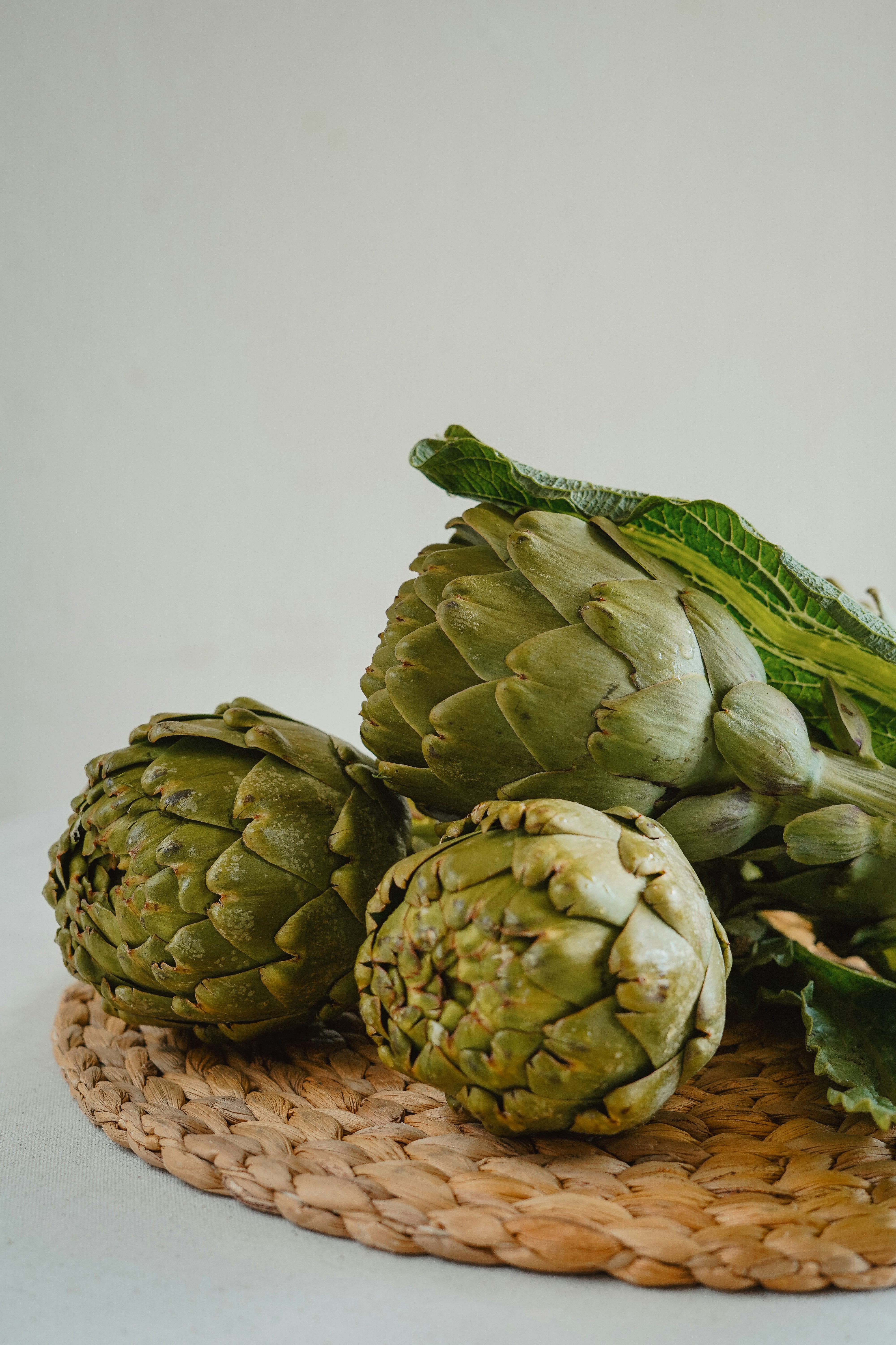 Fresh artichokes on a rustic woven mat.