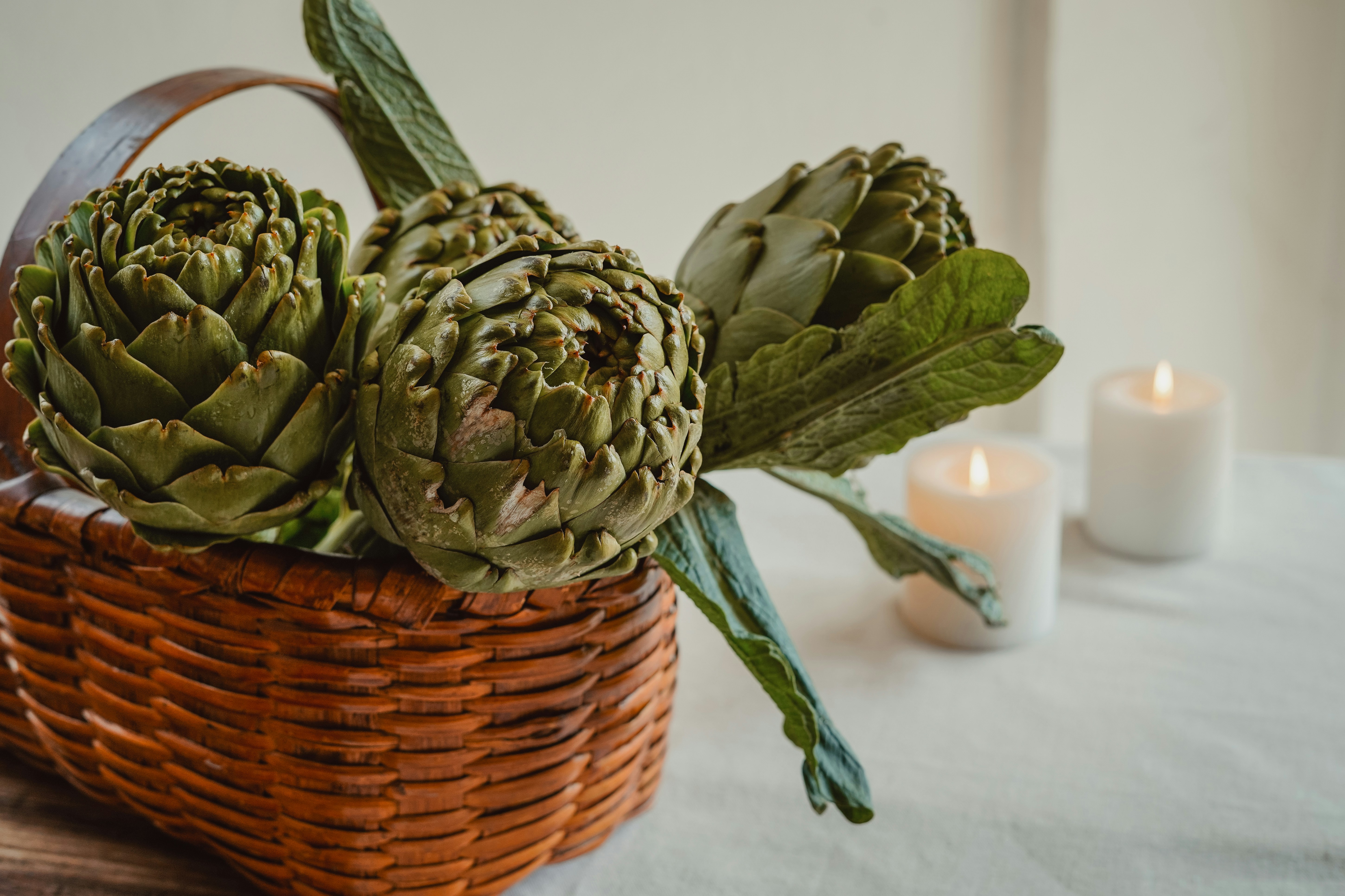 Frische Artischocken sitzen in einem geflochtenen Korb.
