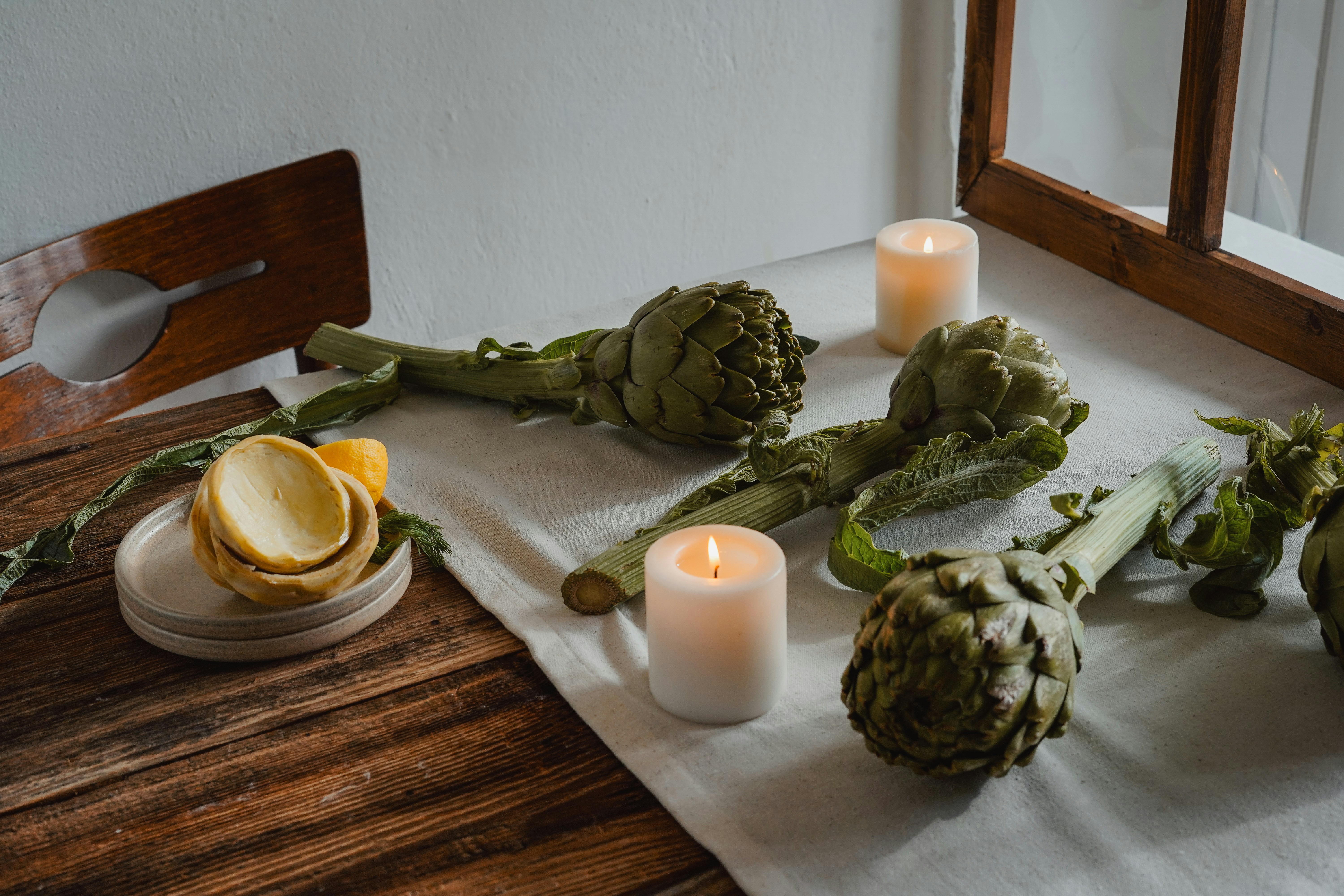 Artischocken und Kerzen sorgen für ein rustikales Stillleben.