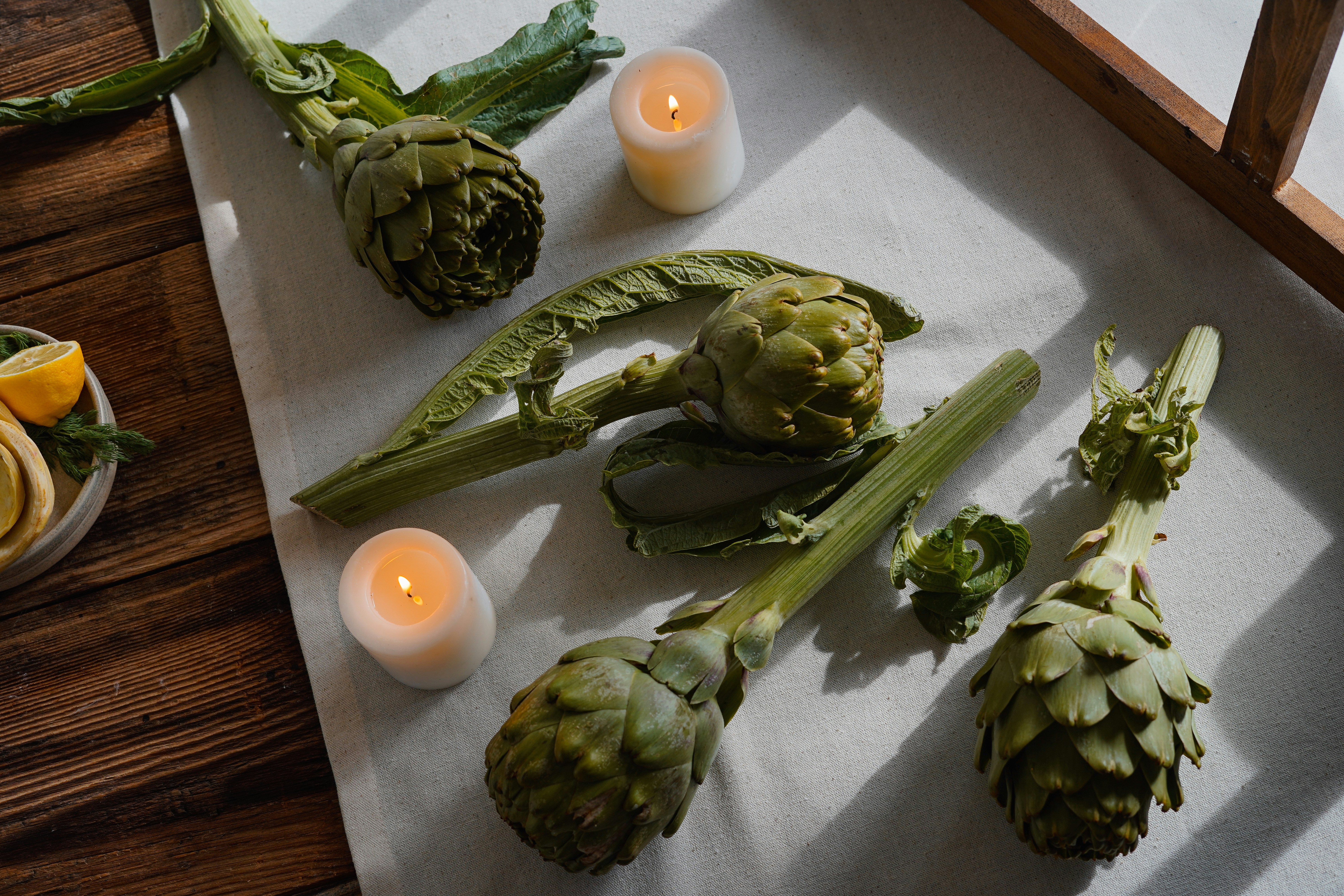 Artischocken und Kerzen sind auf einem Tisch arrangiert.