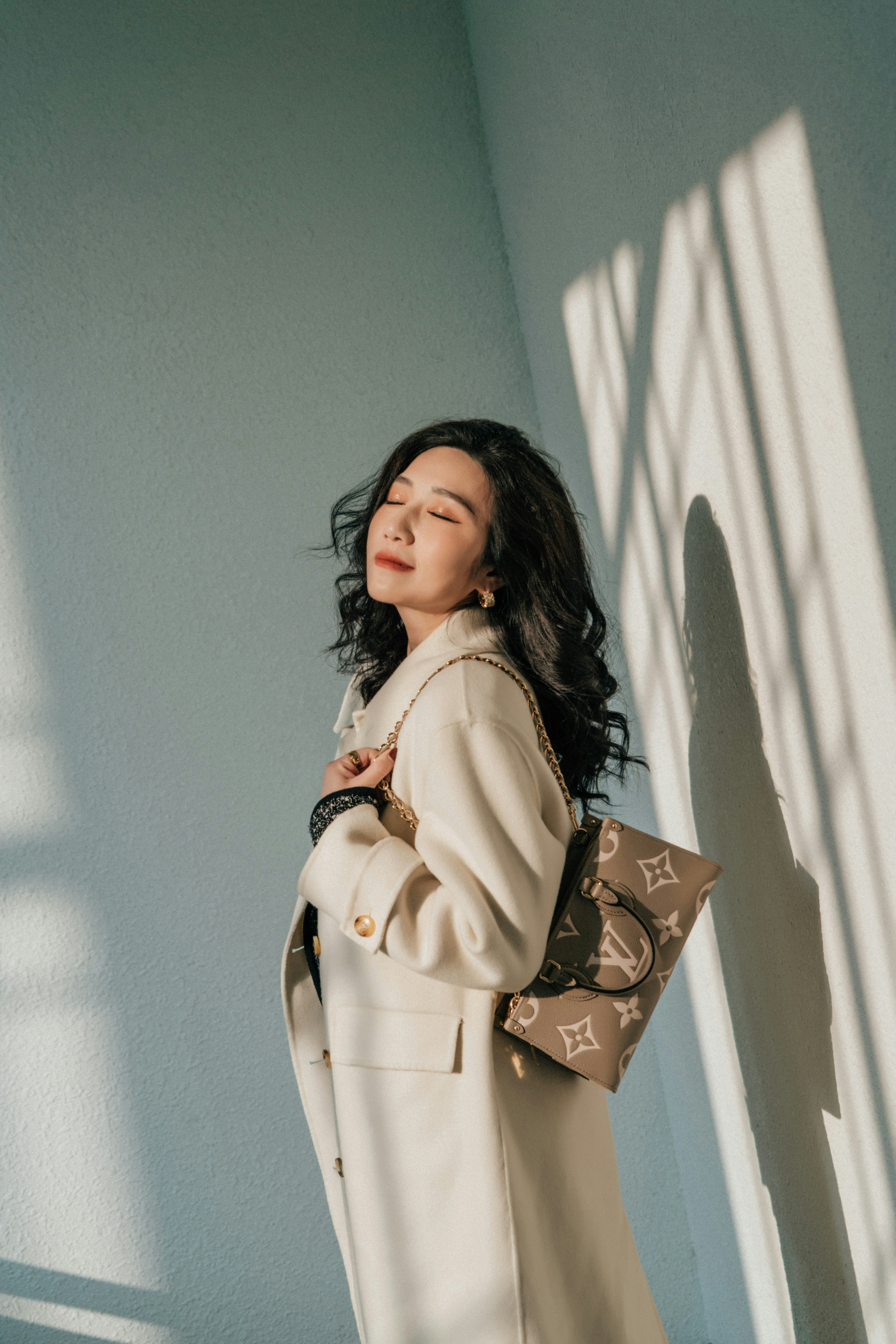 A woman poses with a designer handbag.
