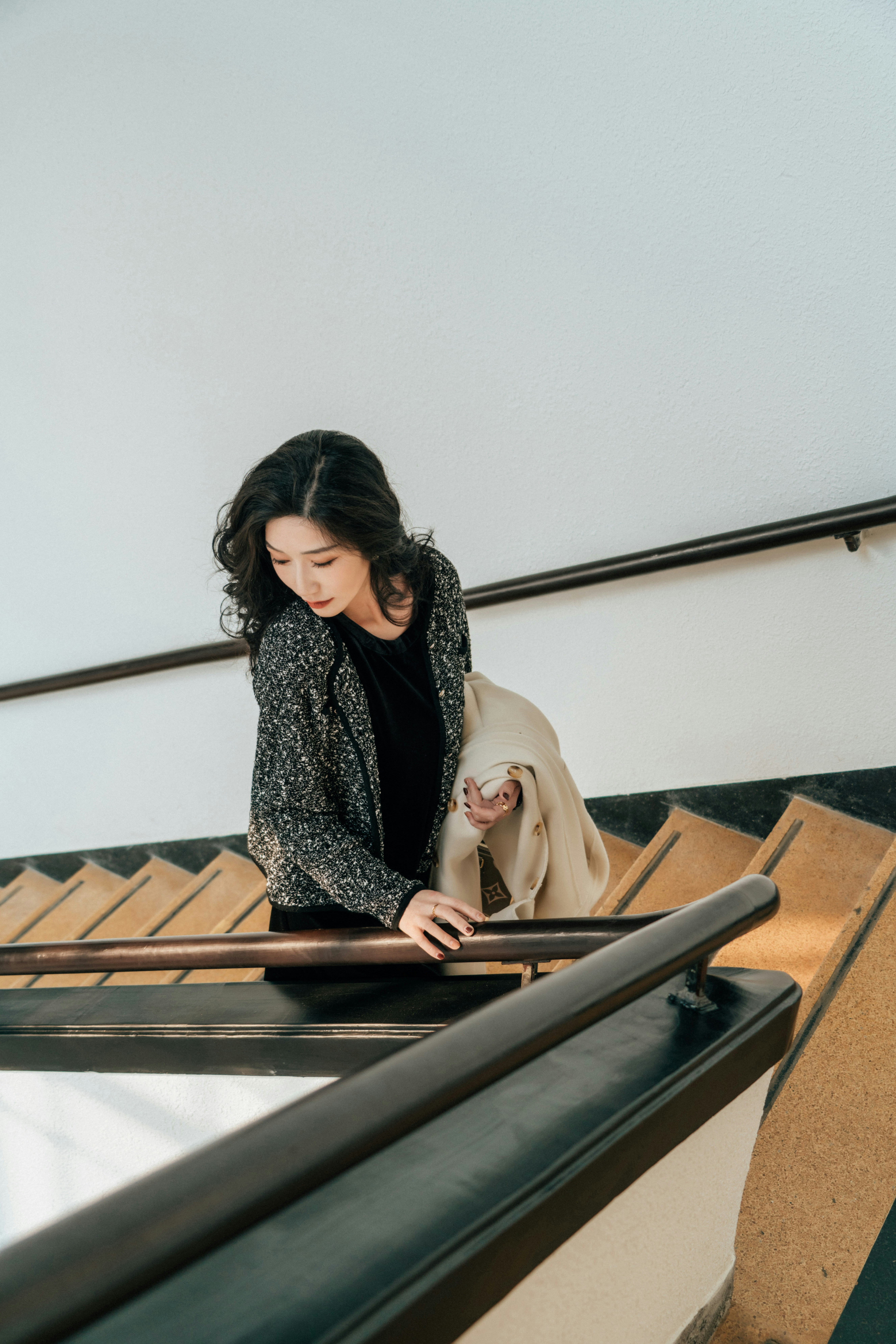 한 여자가 코트를 입고 계단을 내려간다. 사진 – Unsplash의 무료 유행 이미지