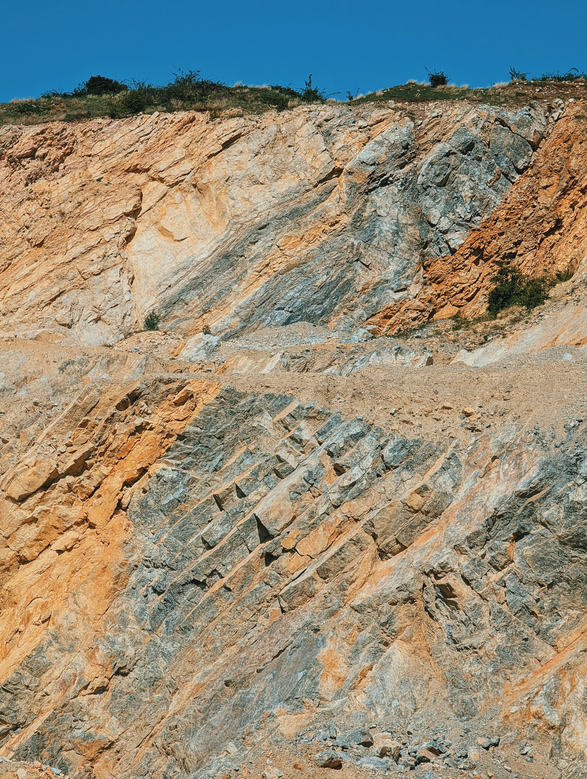 Rocky layers on the cliff against a bright blue sky.
