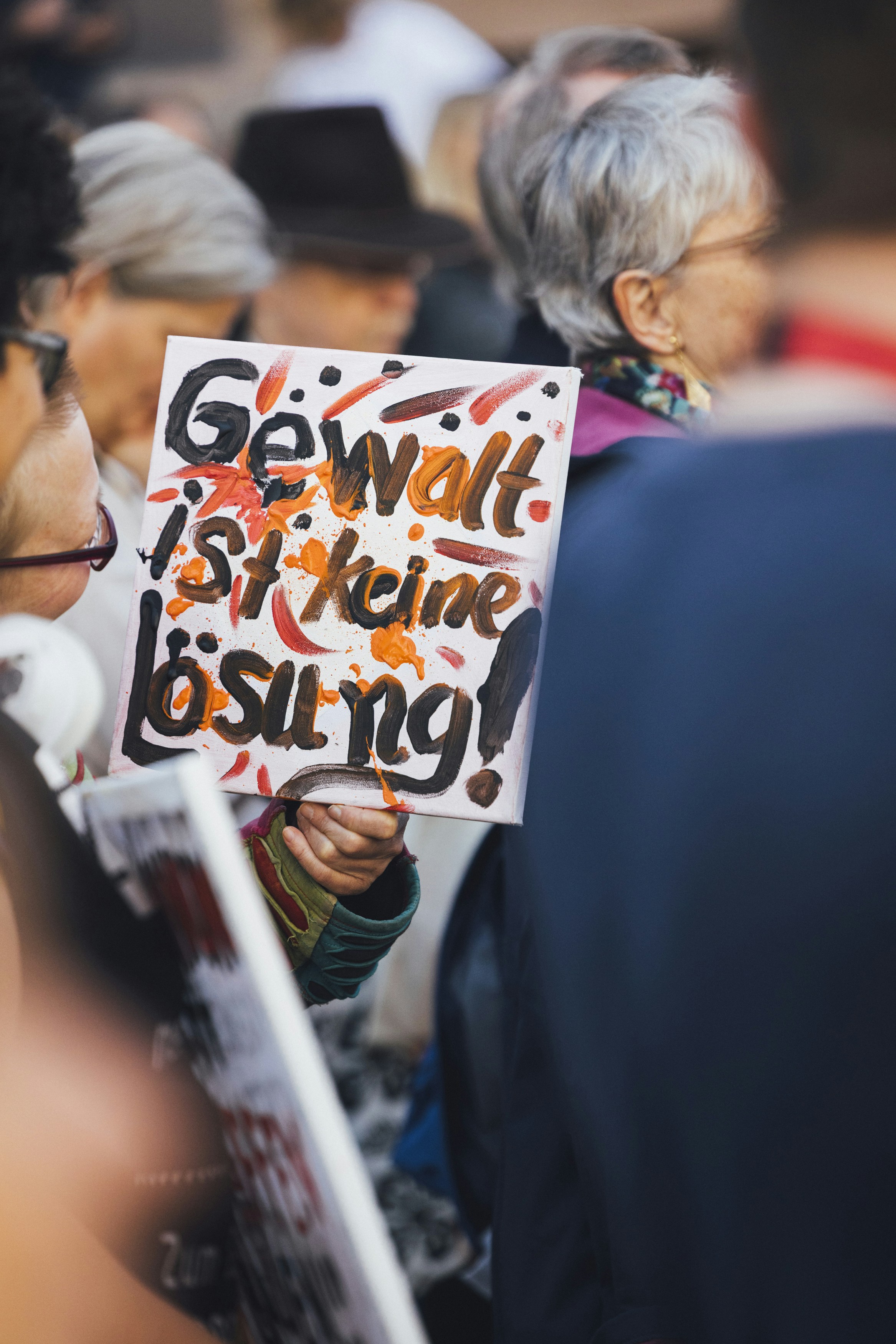 Protesters hold a sign against violence in german.