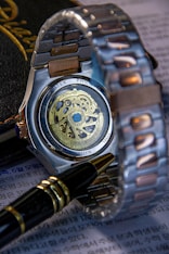 A wristwatch, pen, and paperwork are artfully arranged.