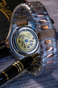 A wristwatch, pen, and paperwork are artfully arranged.