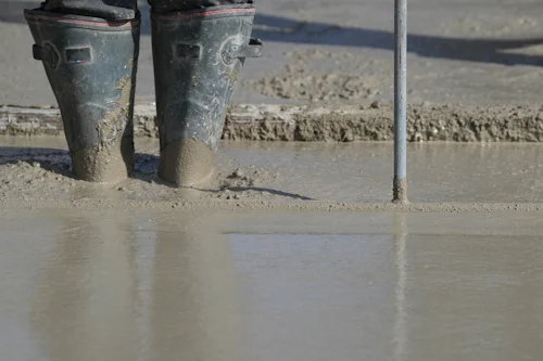 Worker's boots standing in wet screeded concrete