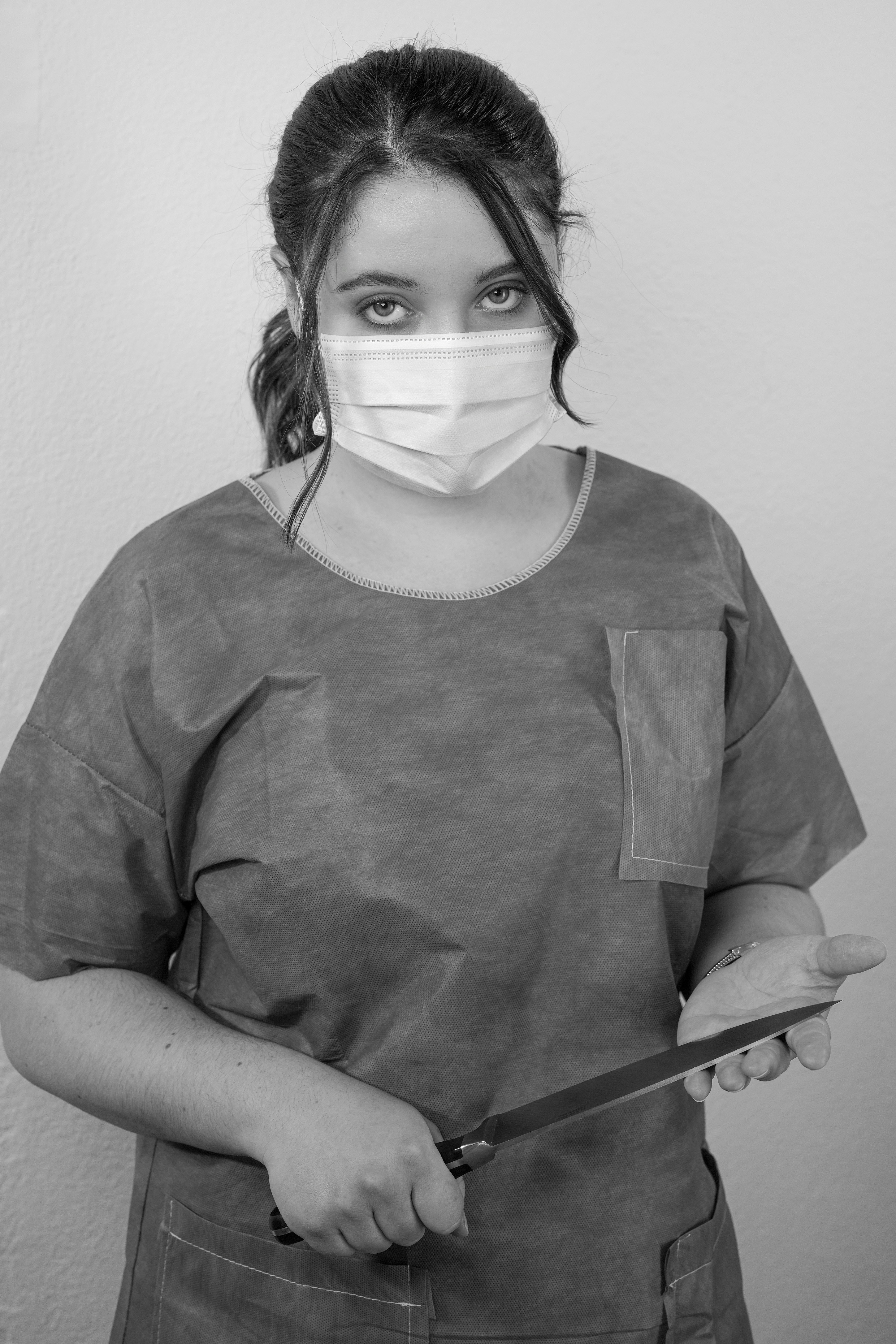 Surgeon stares, holding a knife.