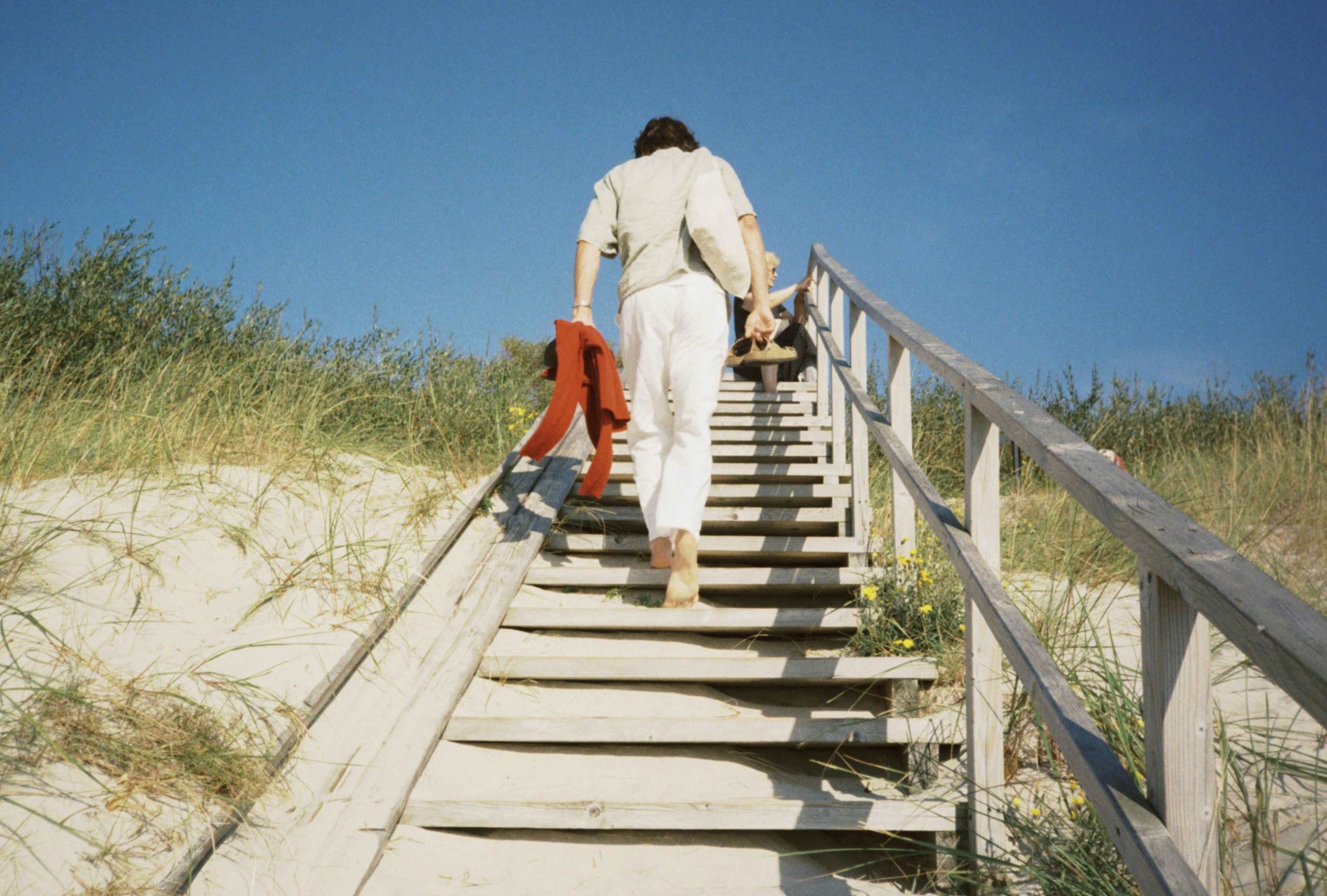 Person climbs stairs towards a sunny sky