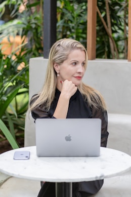 A woman contemplates while working on her laptop.