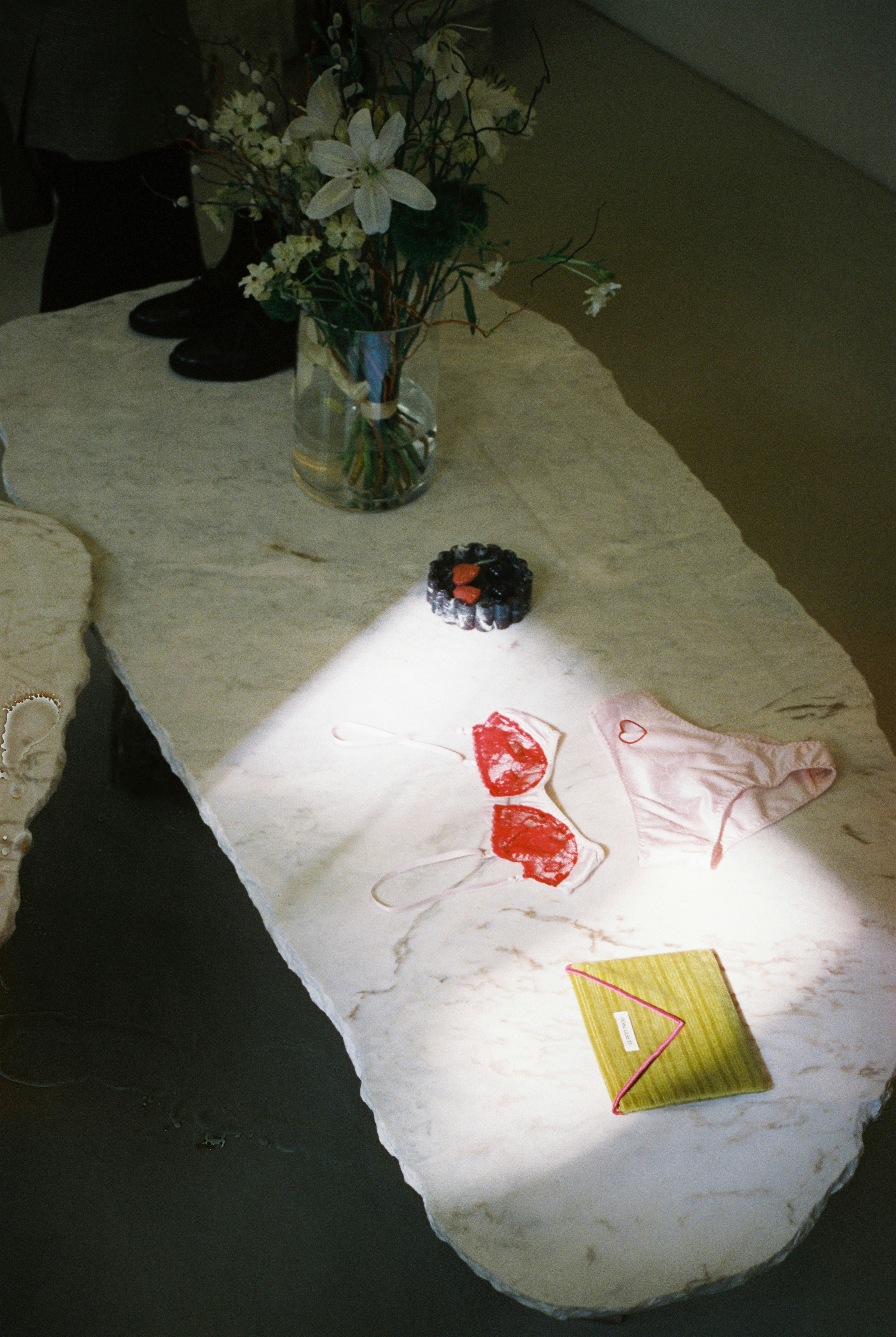 Lingerie and flowers are arranged on a marble table.