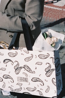 Someone holds a shopping bag with flowers.