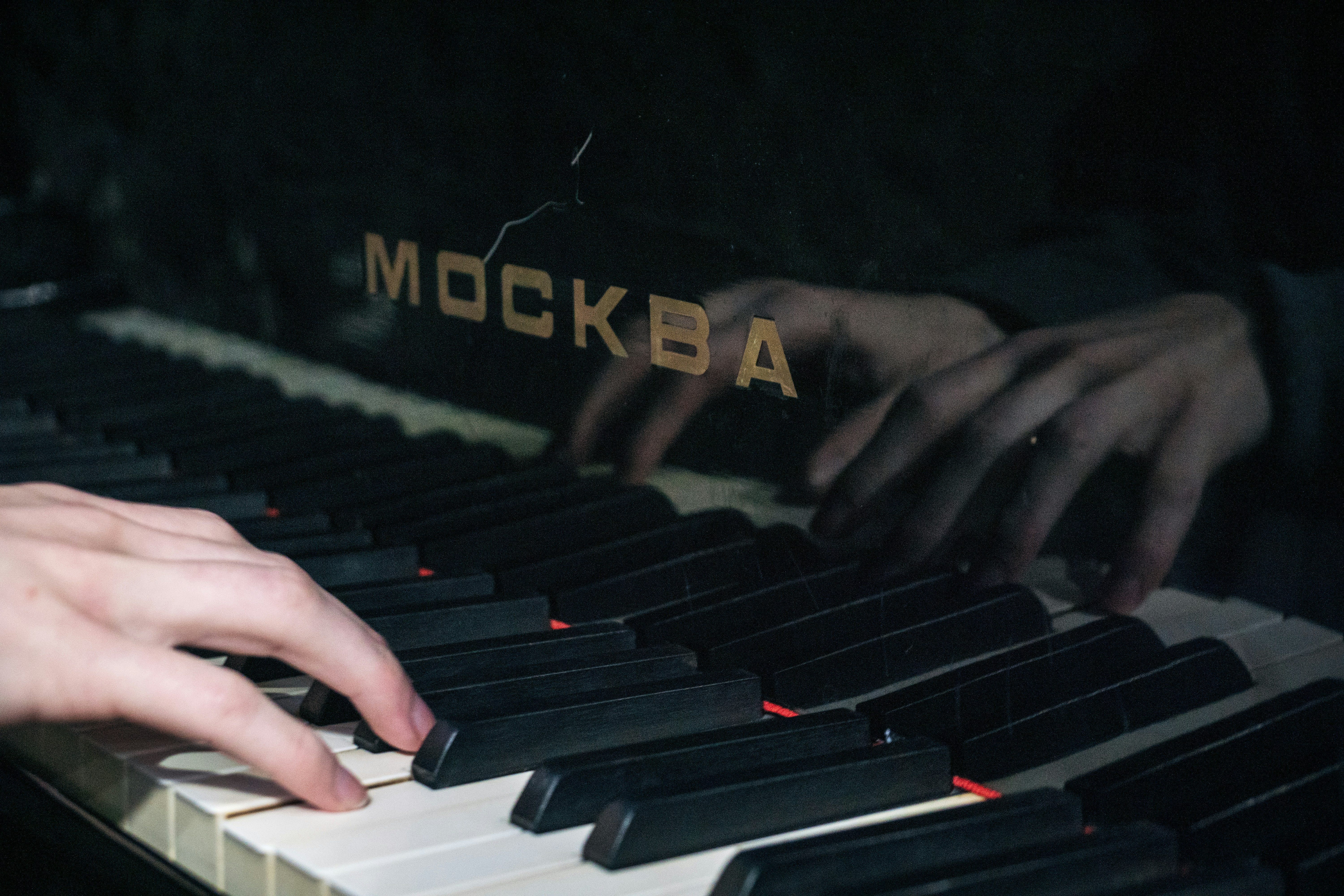 Hands are playing a piano with the name 