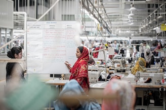 A woman in a factory stands by a whiteboard.
