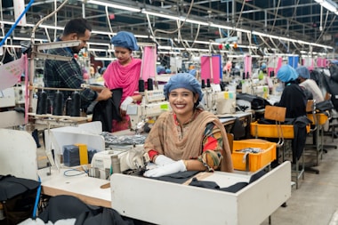 Workers are sewing clothing in a busy factory.