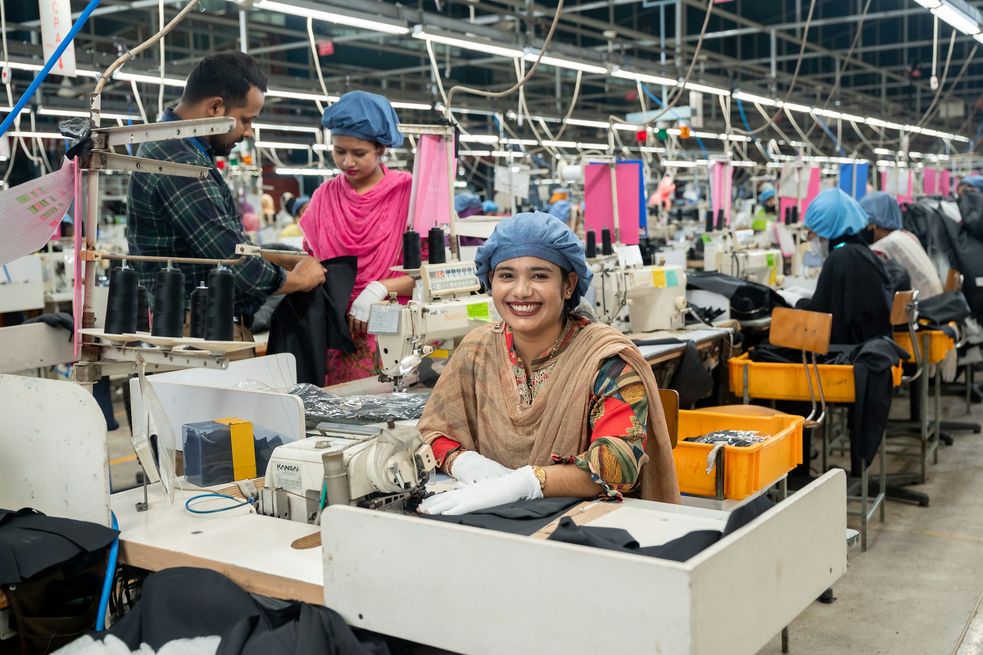Workers are sewing clothing in a busy factory.