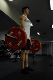 A man is lifting heavy weights at the gym.