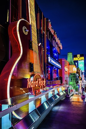 The hard rock cafe guitar sign is glowing at night.