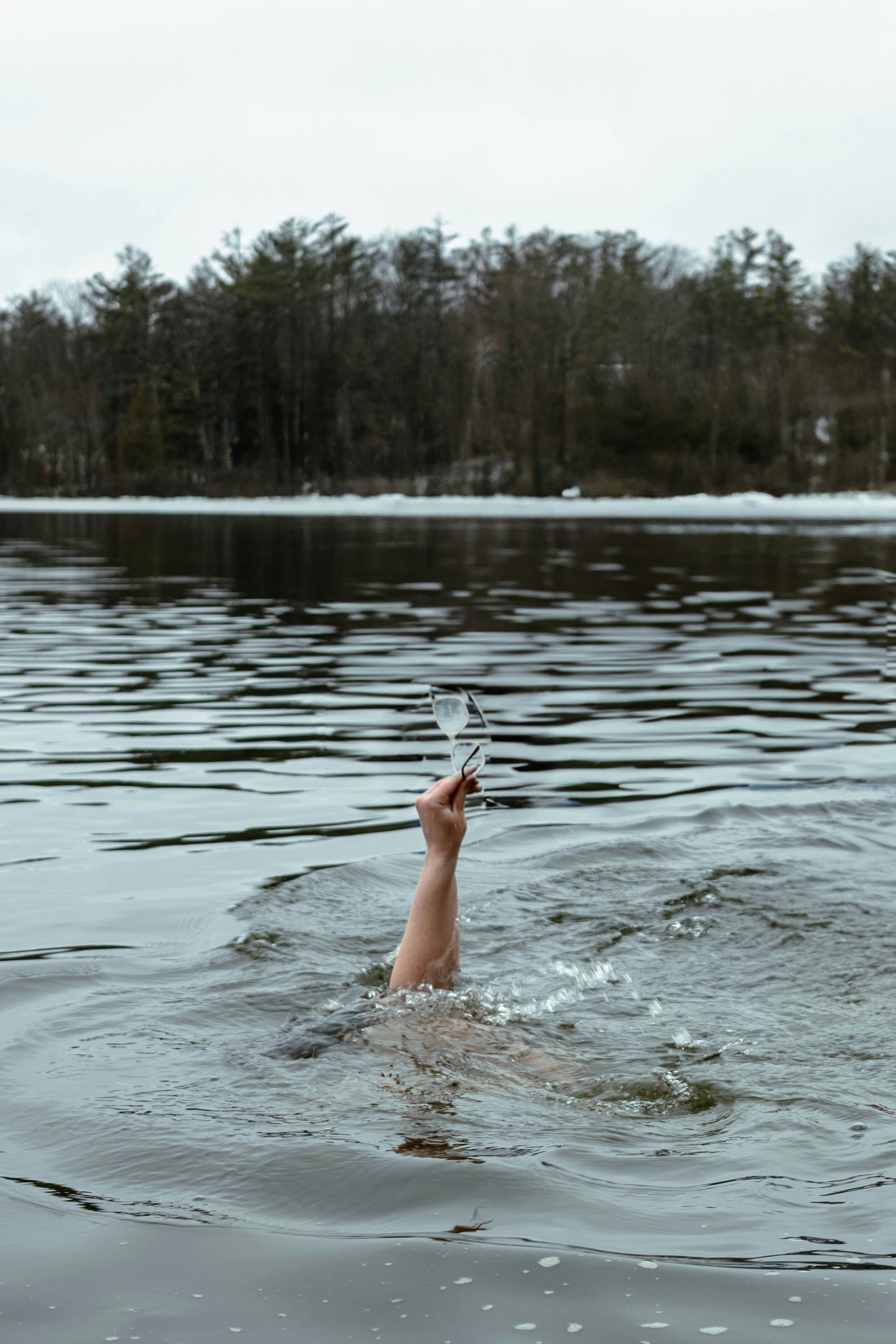 A hand raises a glass from the water.