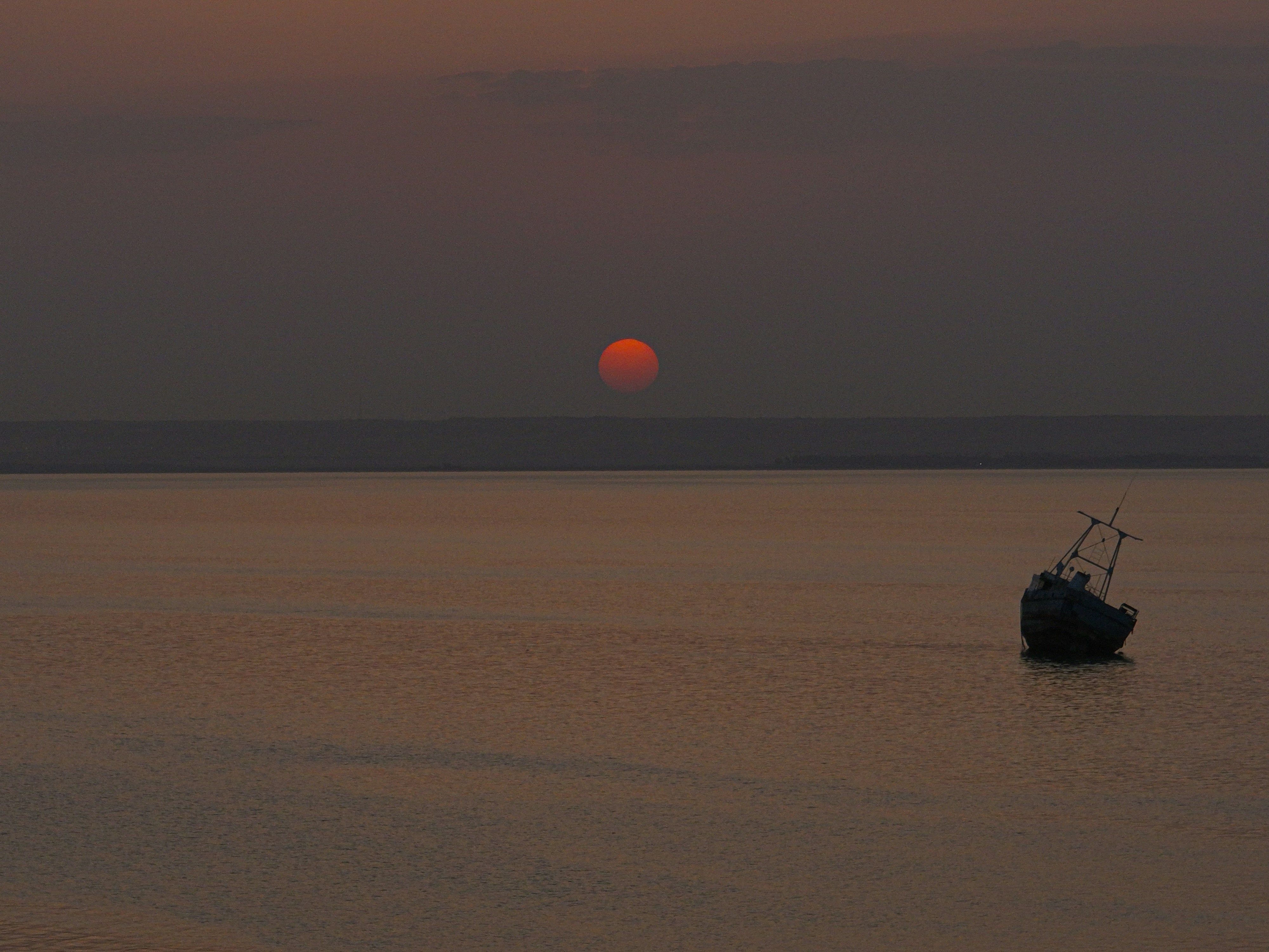 Boat floating peacefully on the water during a seasonal sunset