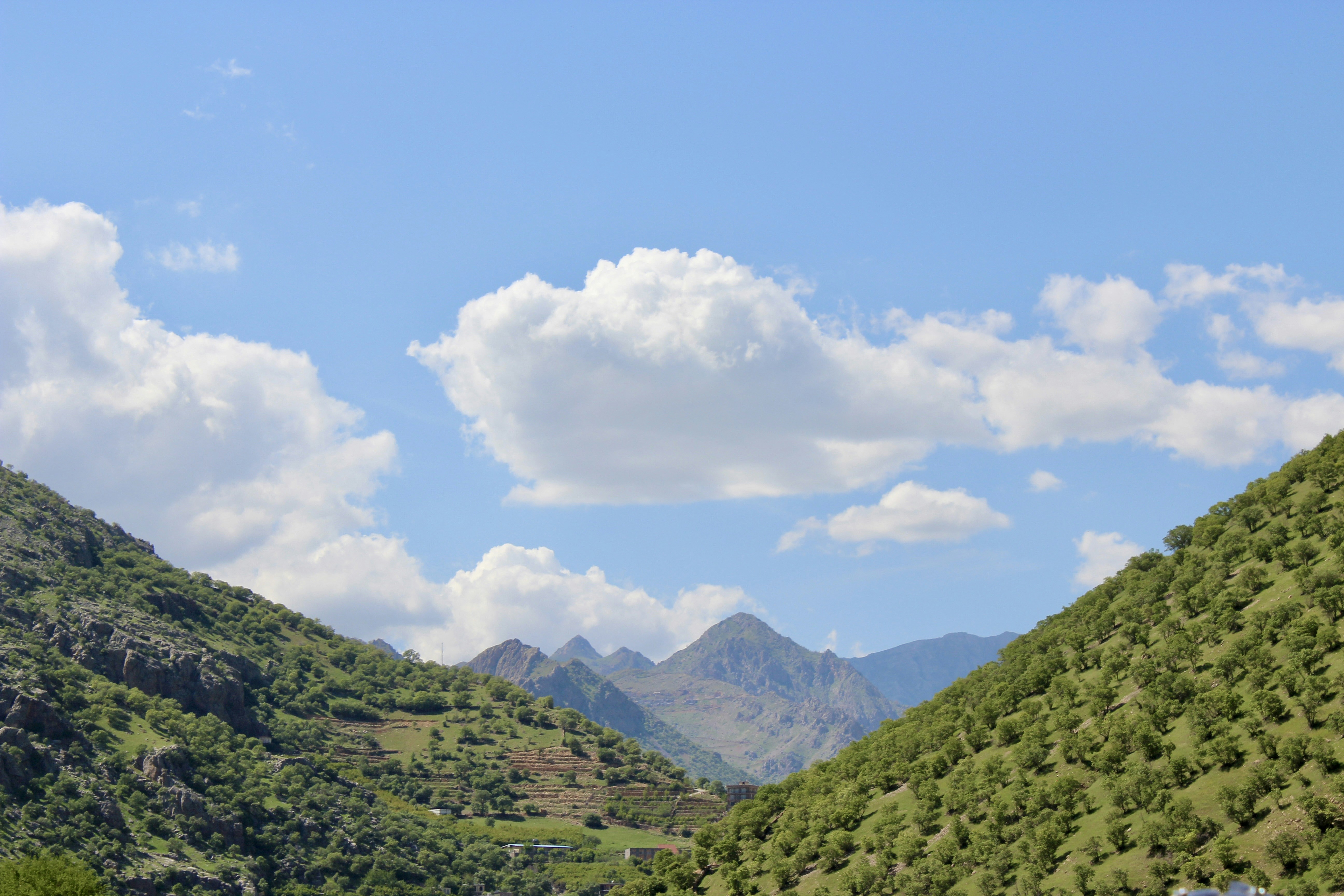 Mountains and puffy clouds fill the scenic landscape., 
