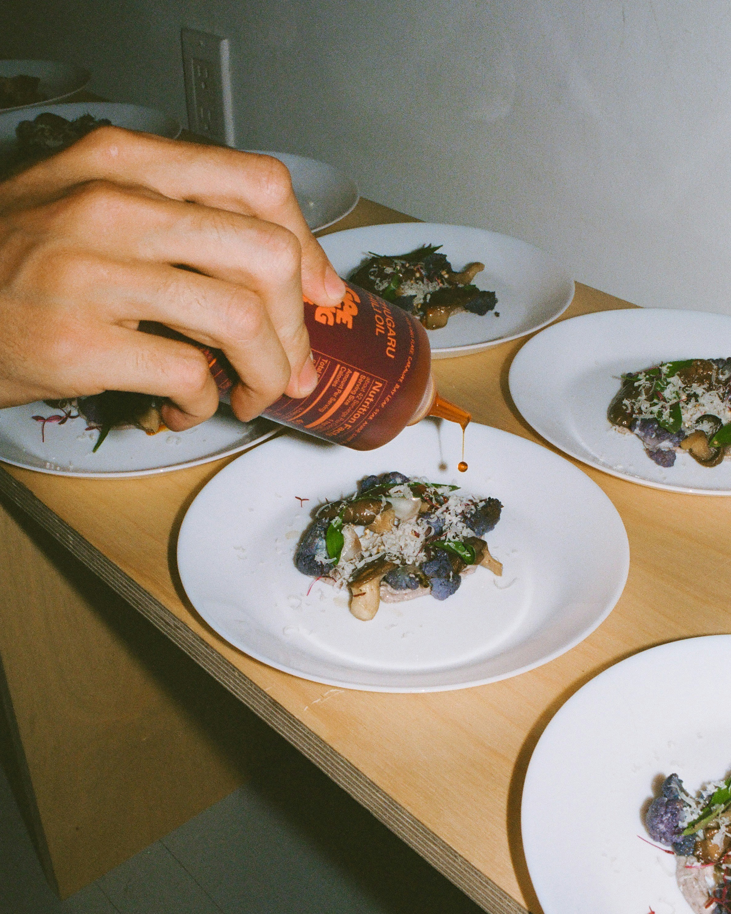Sauce being poured onto plated gourmet food