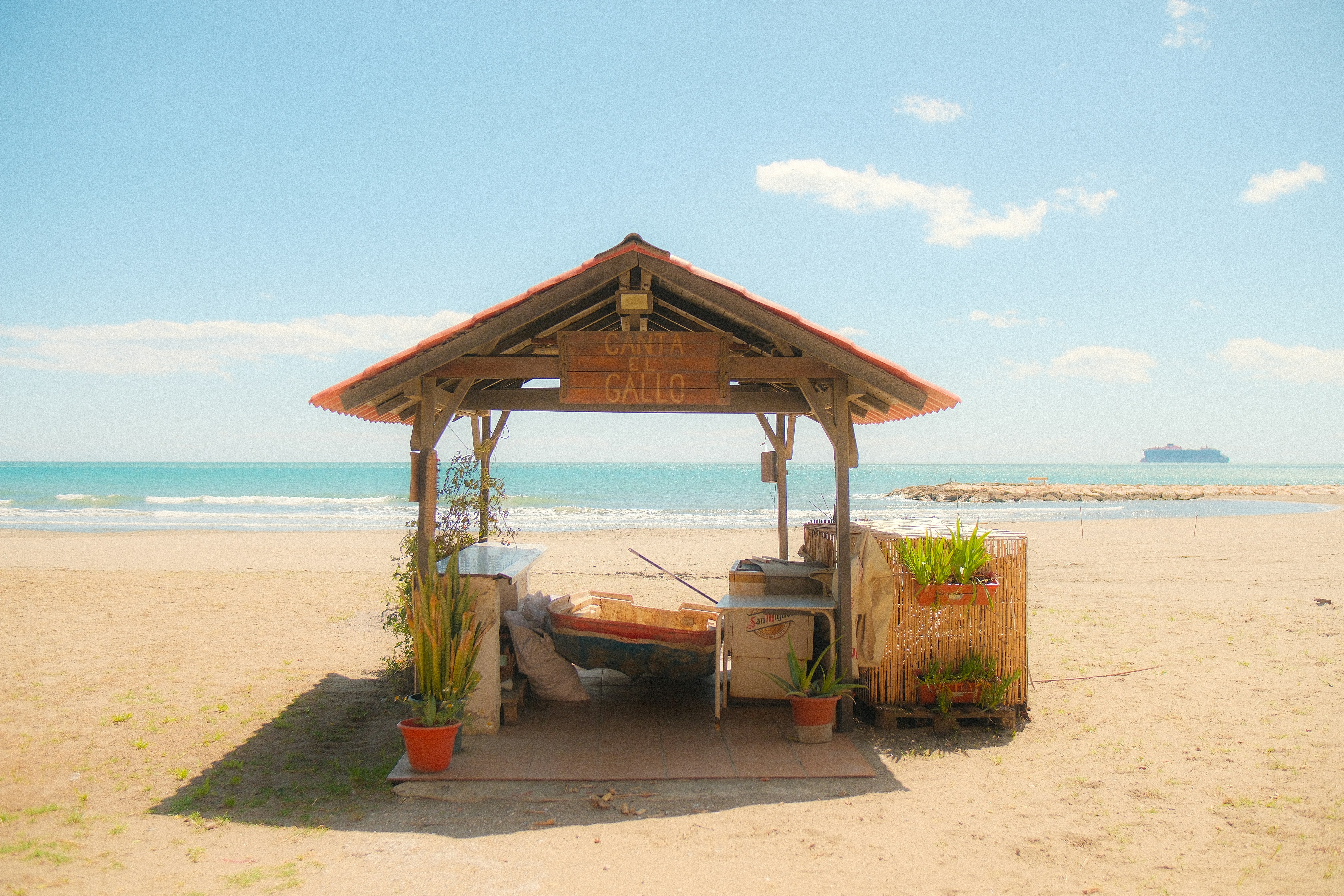 A beach hut stands beside the ocean.