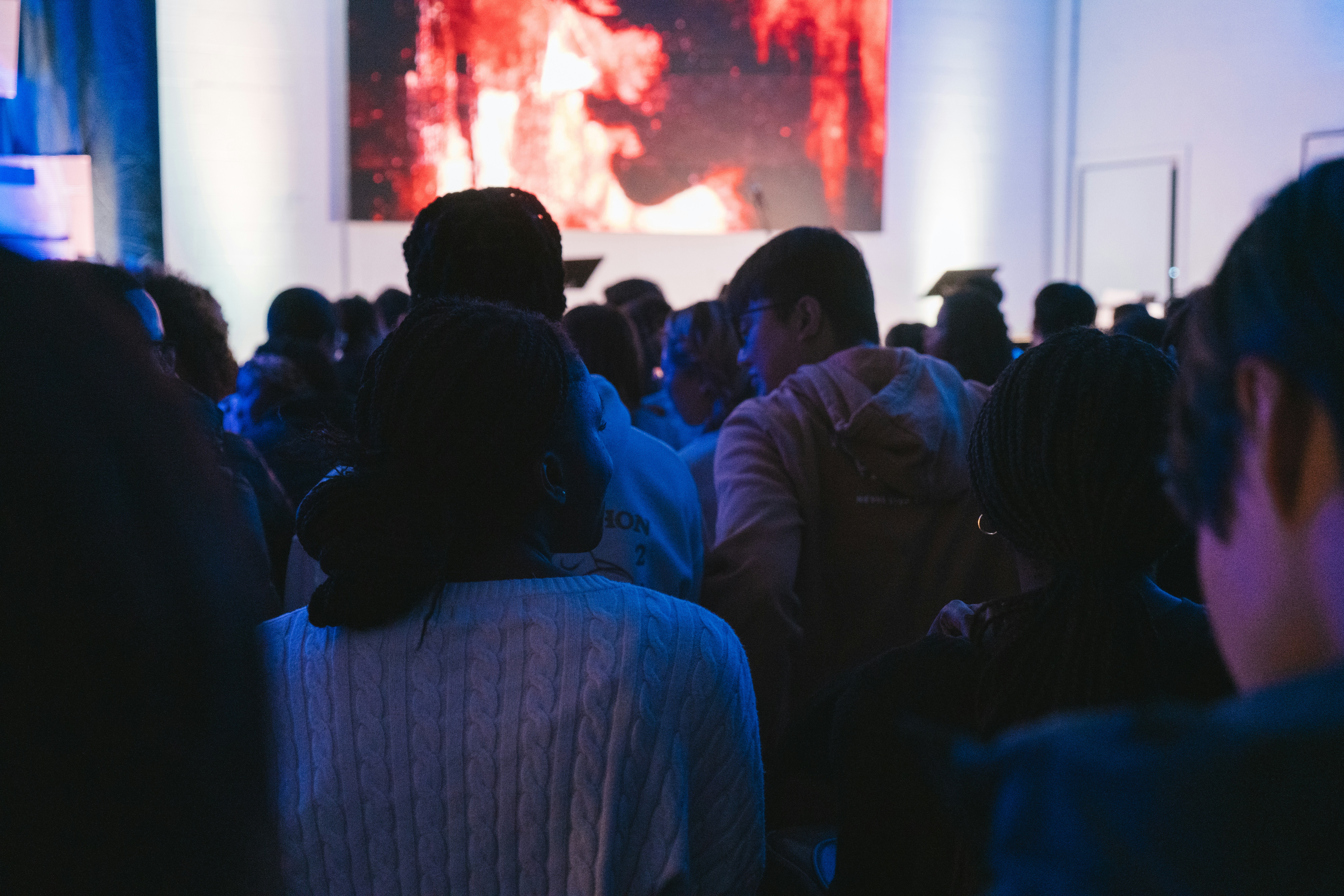 People watch something projected on a large screen.
