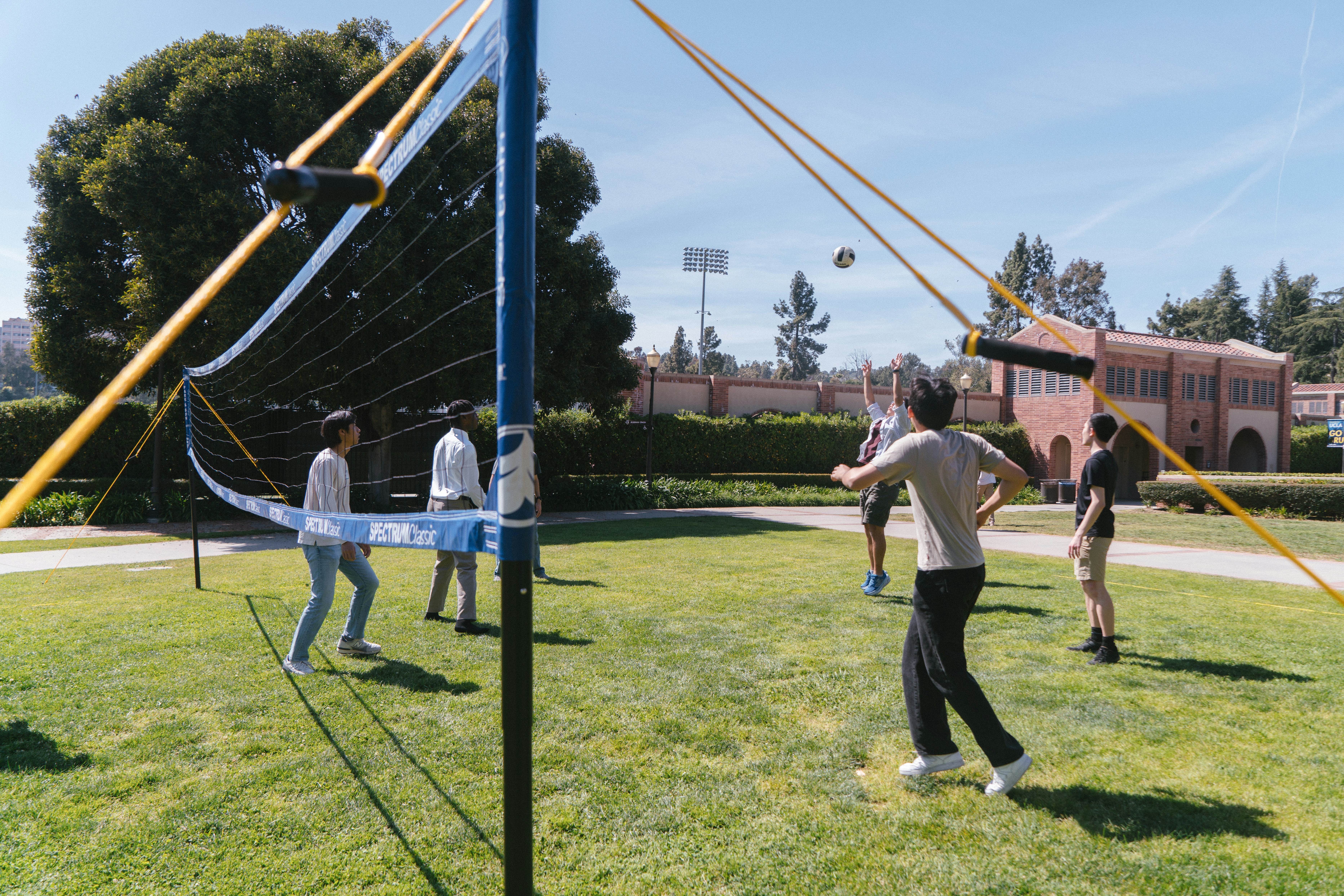 People are playing volleyball outdoors on a sunny day.