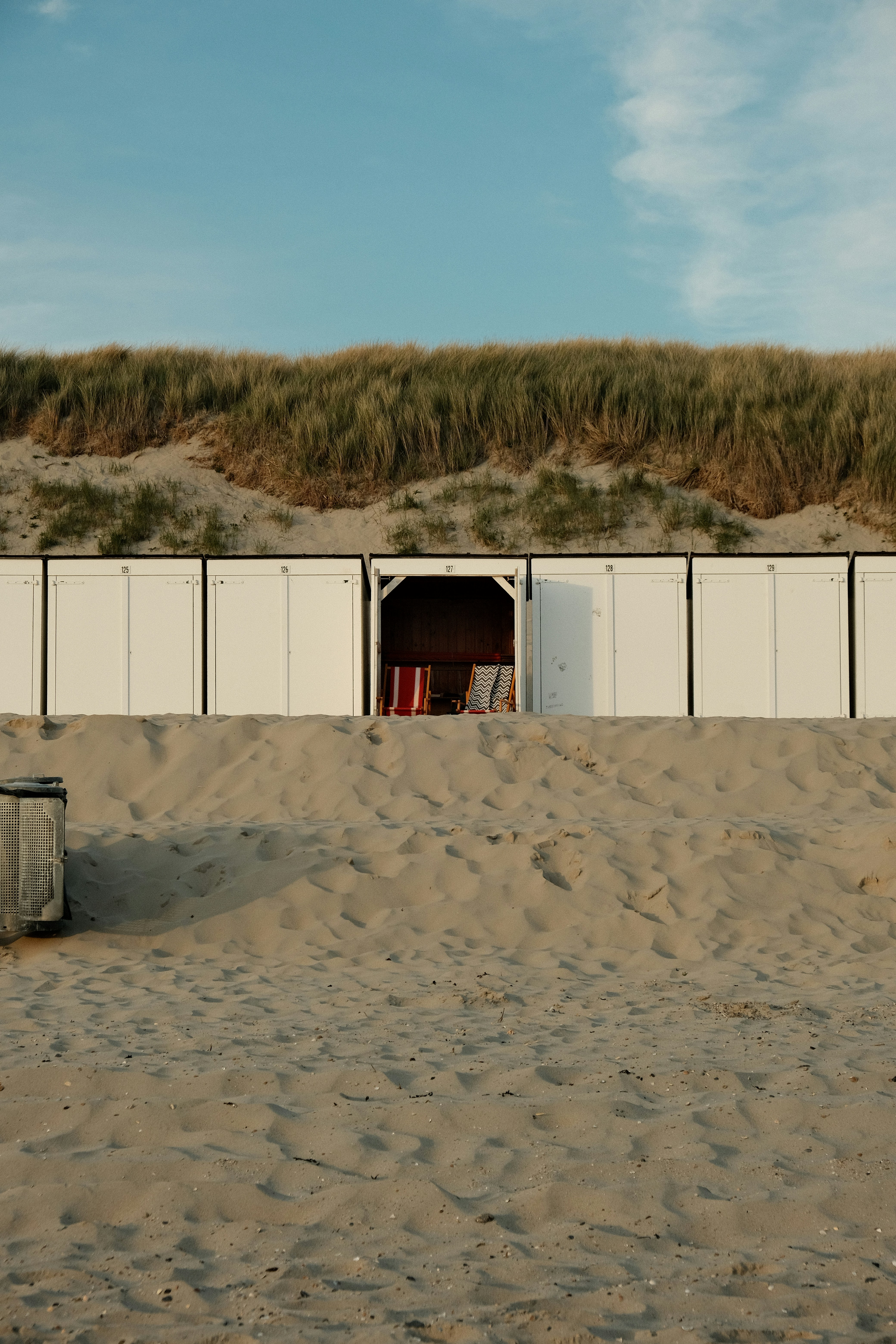 Beach huts are lined up on a sandy shore.