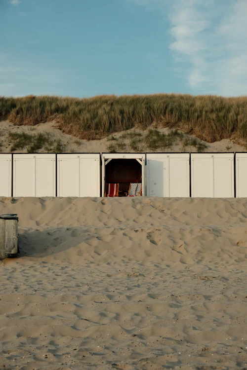 Cabines de plage blanches alignées au pied d'une dune