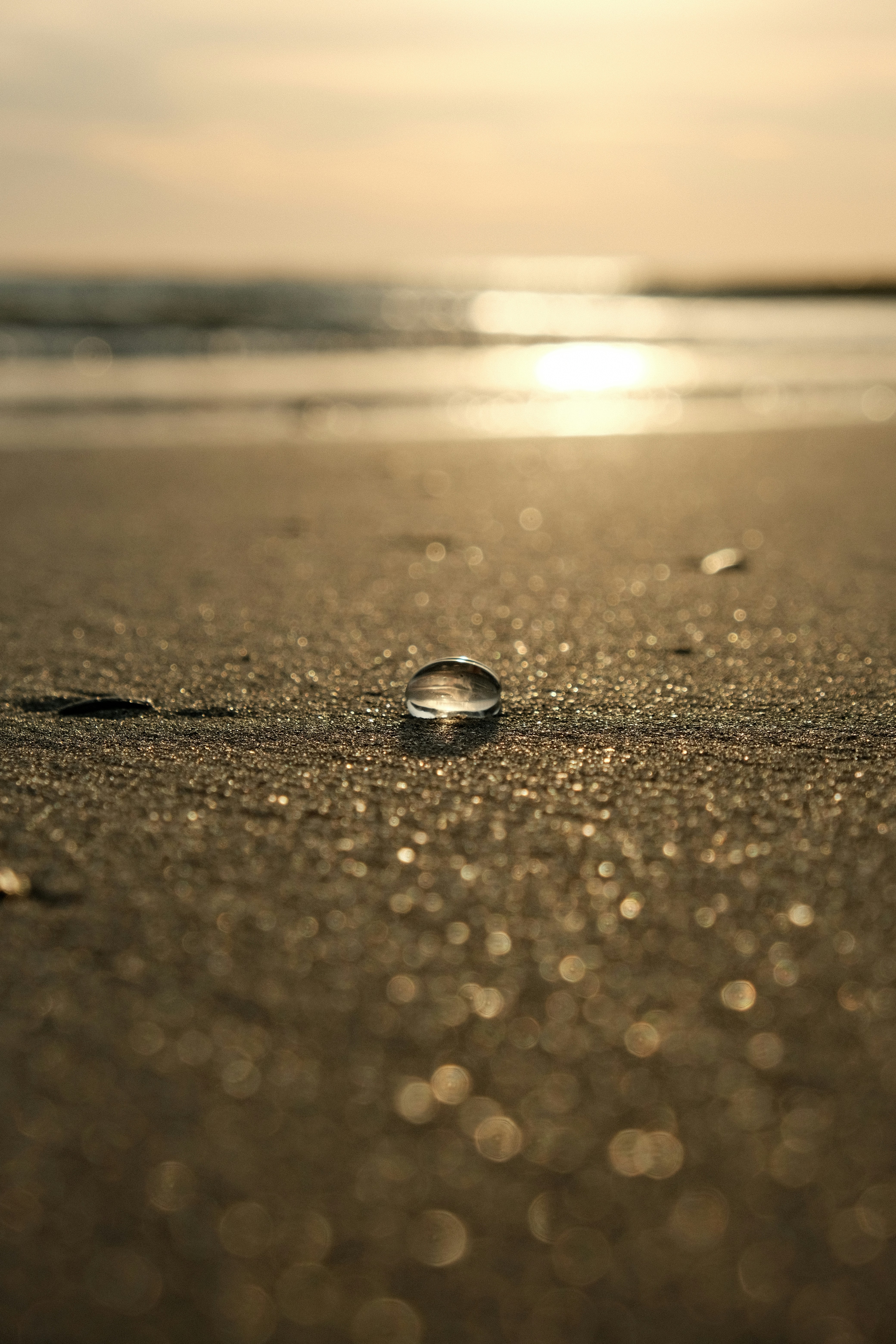 A water droplet sits on the sandy beach.