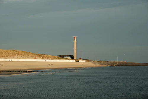 Leuchtturm und langer Sandstrand unter Nordseehimmel