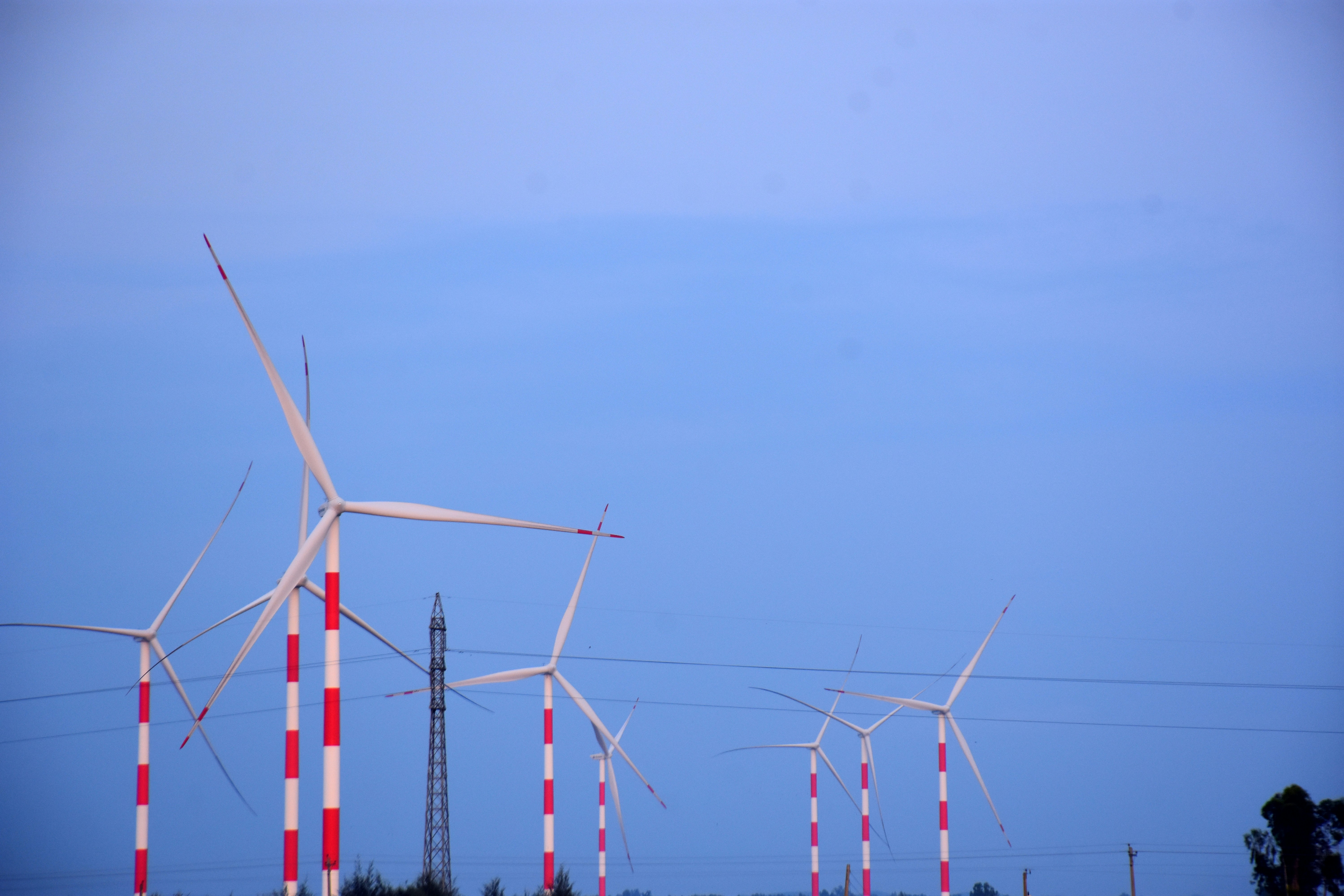 Wind turbines stand tall against a blue sky.