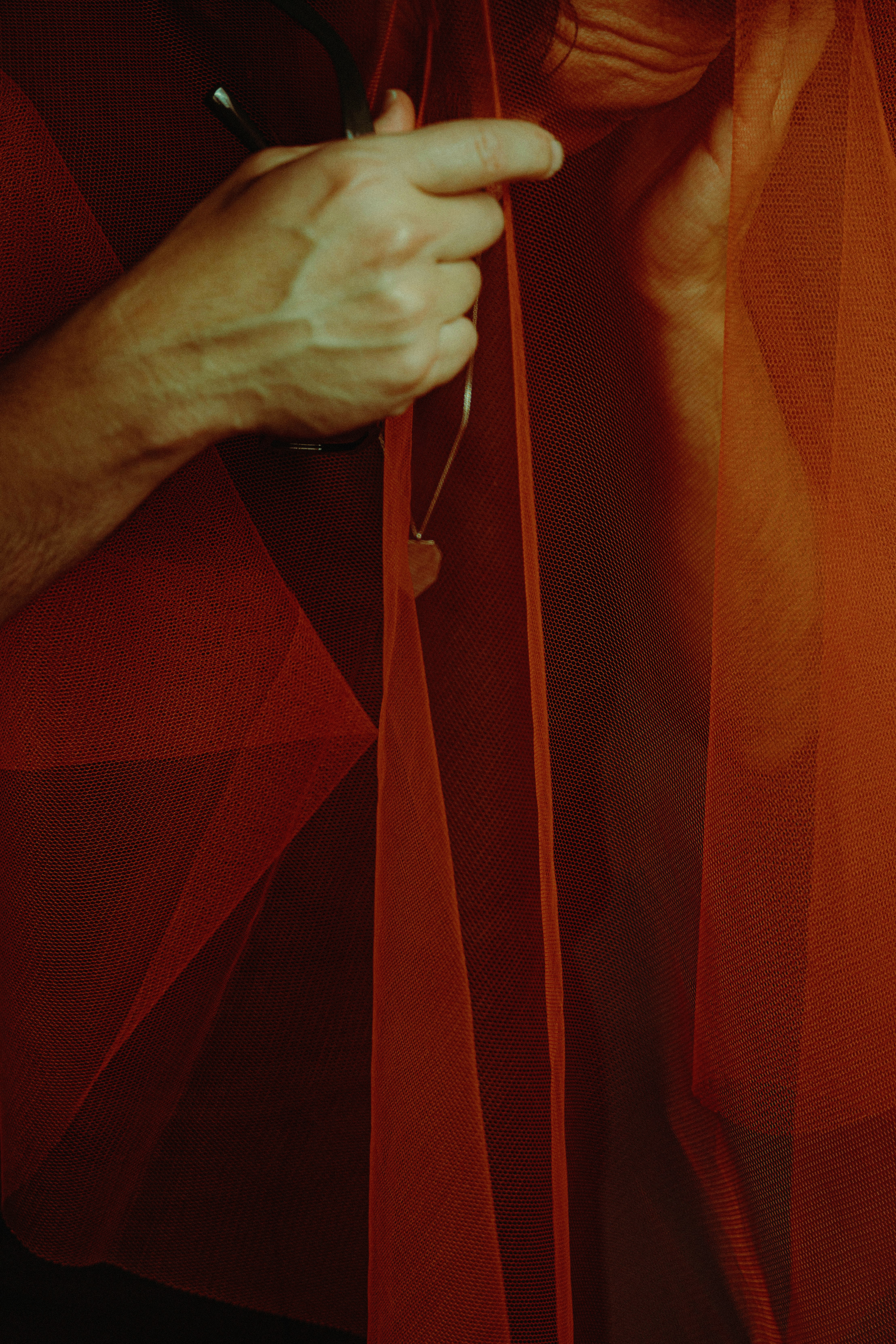 Hands are holding and cutting a red fabric.