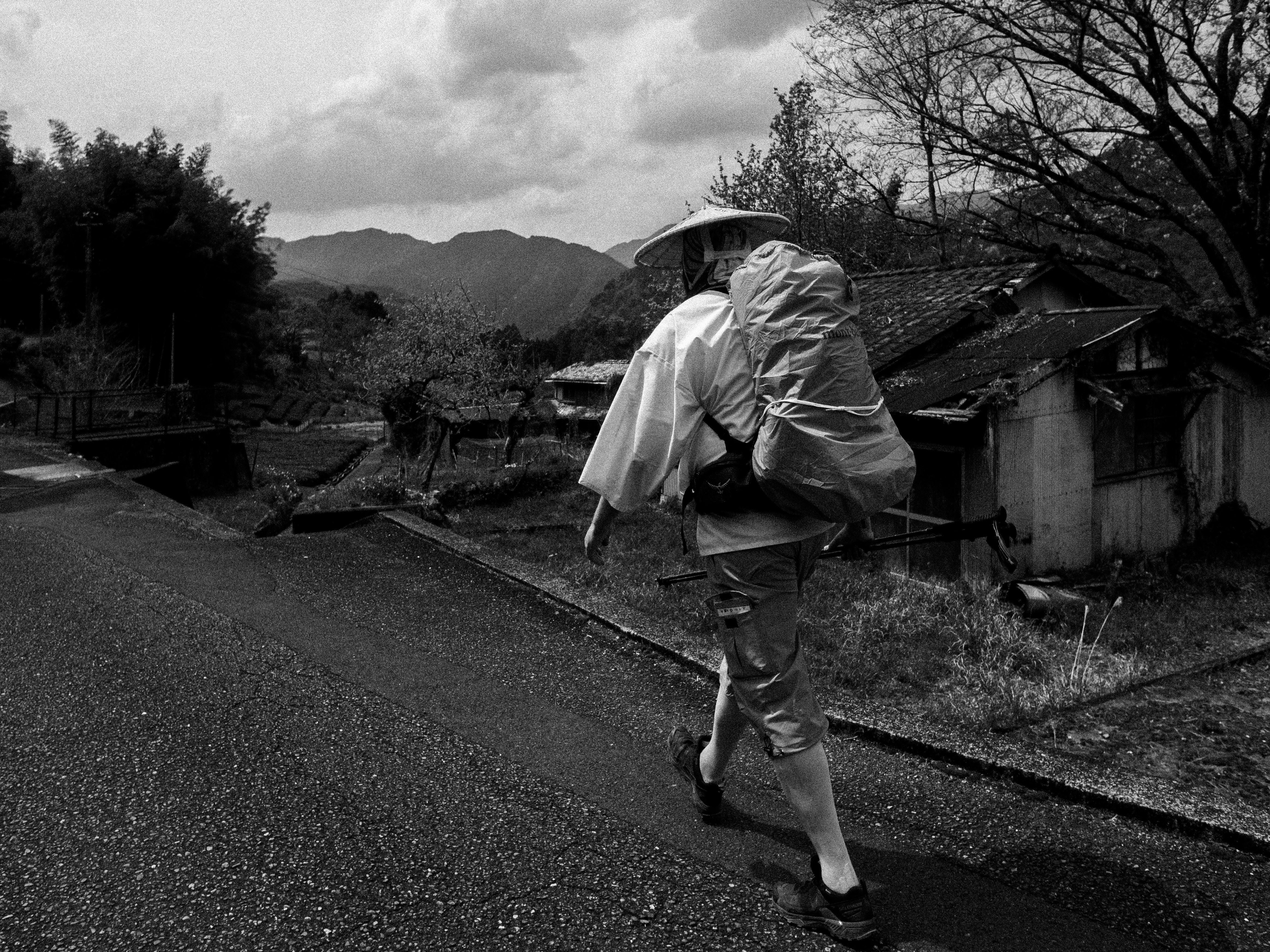 A hiker walks along a road in a rustic scene.