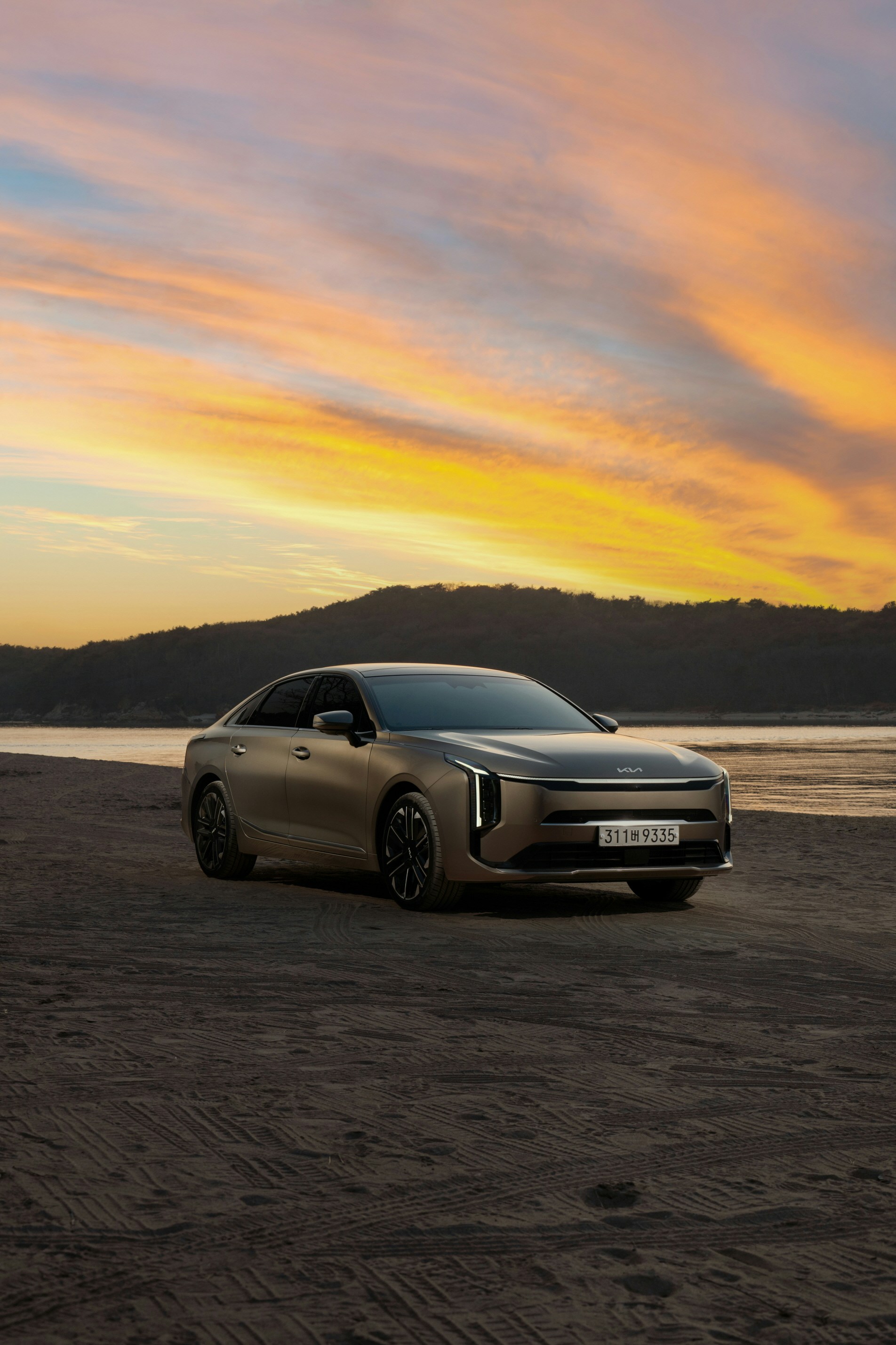A modern car on a beach with a sunset.