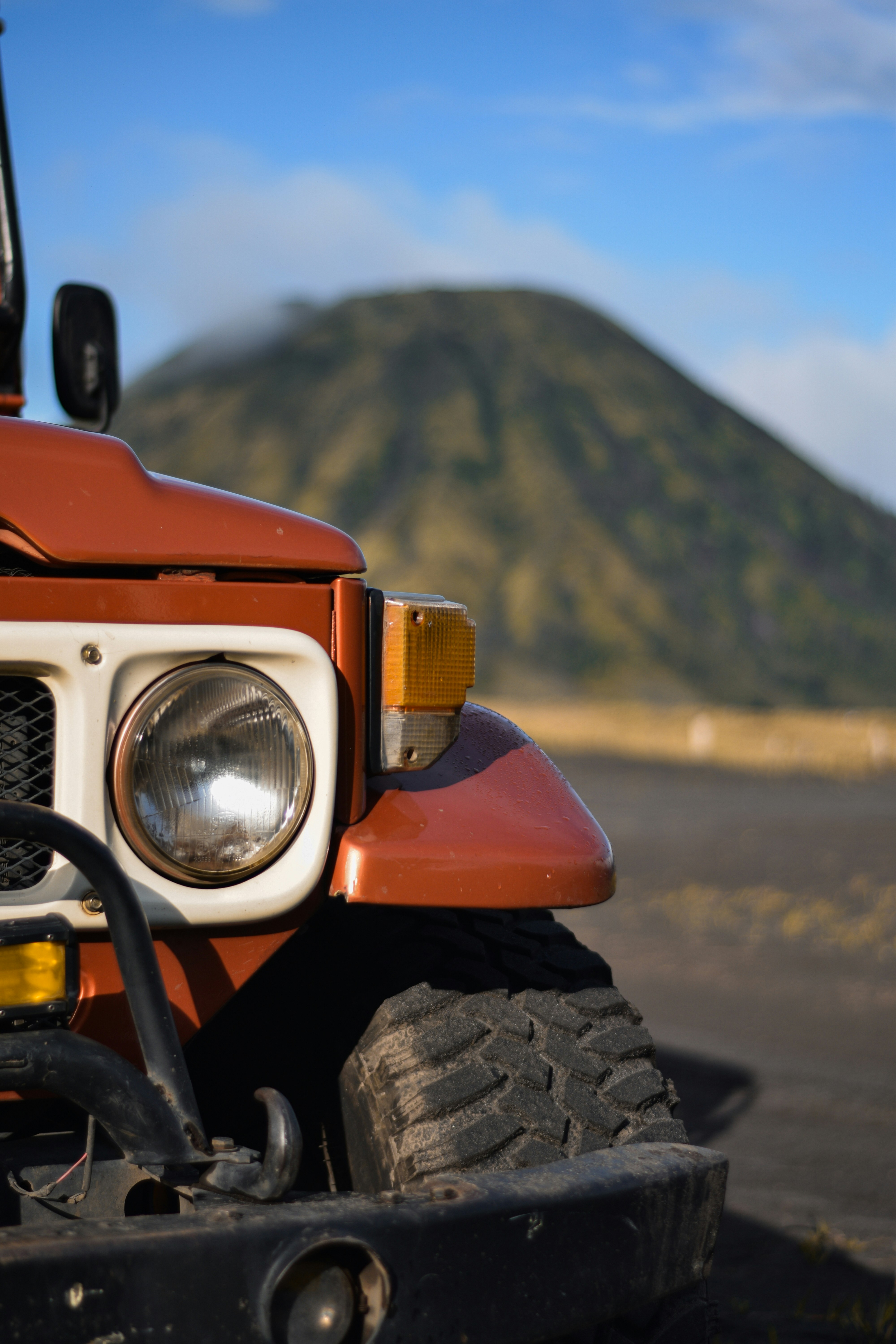 A vintage jeep sits before a mountain.
