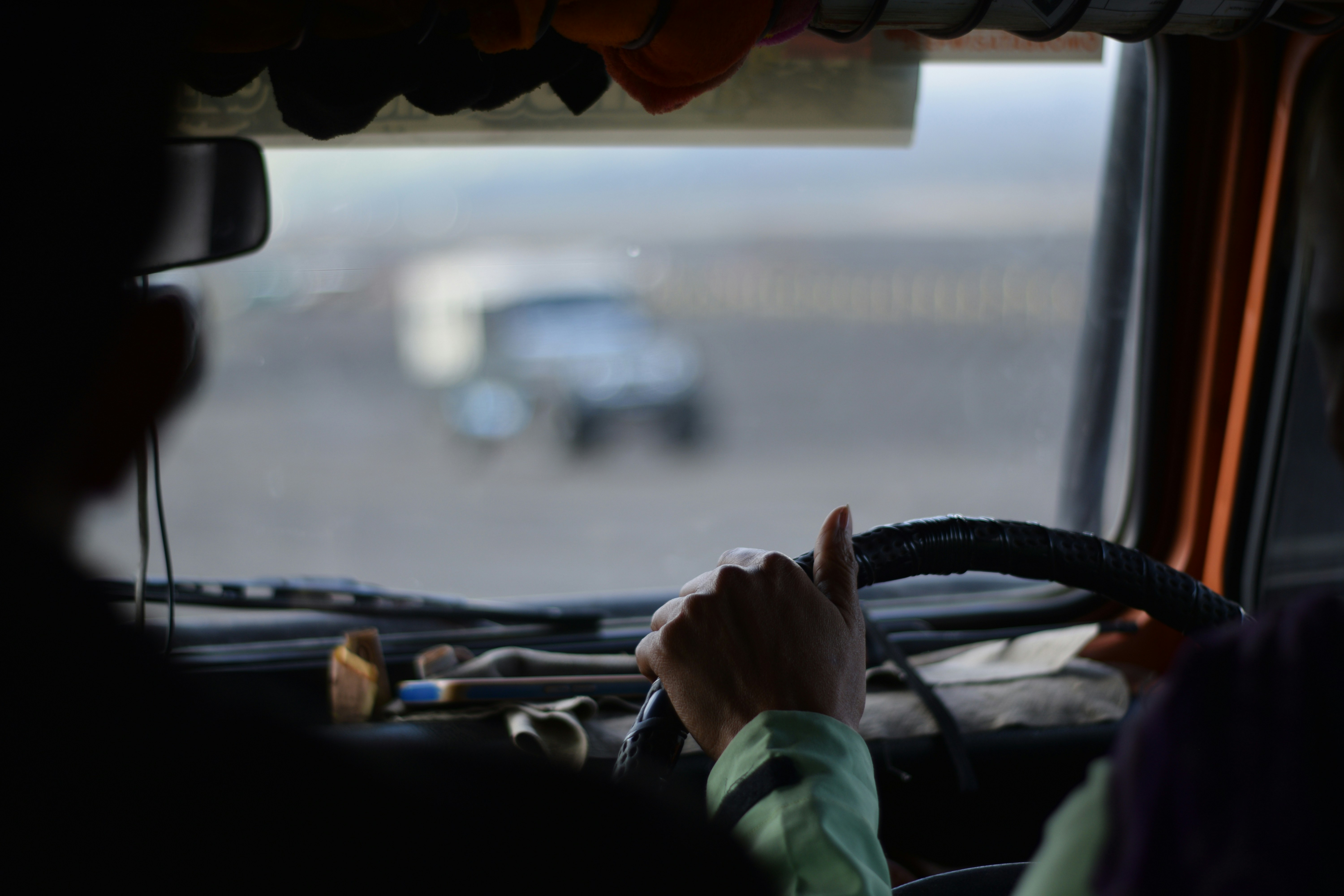 A driver holds a steering wheel and watches ahead.