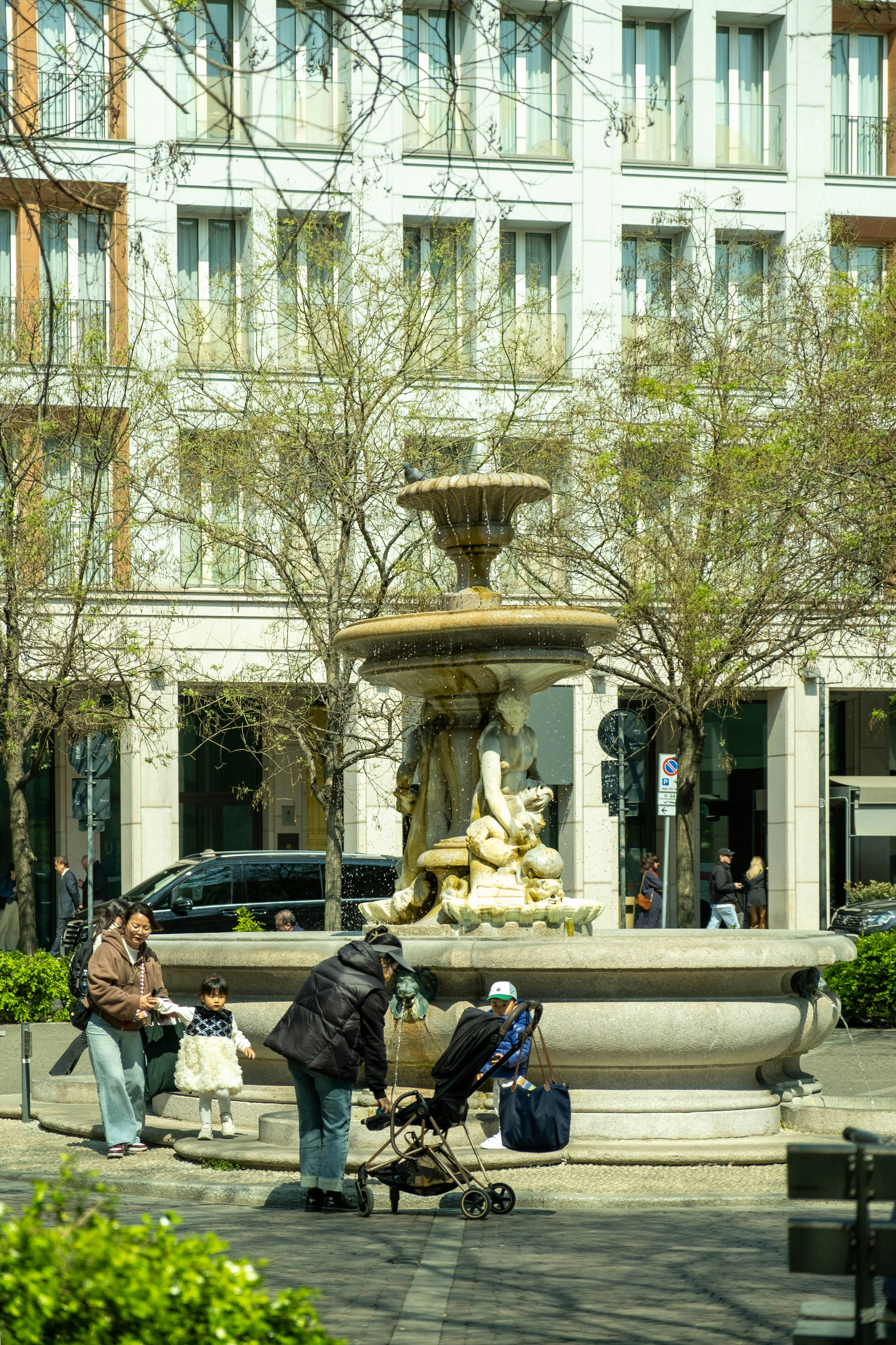People are gathered around a fountain in the city.