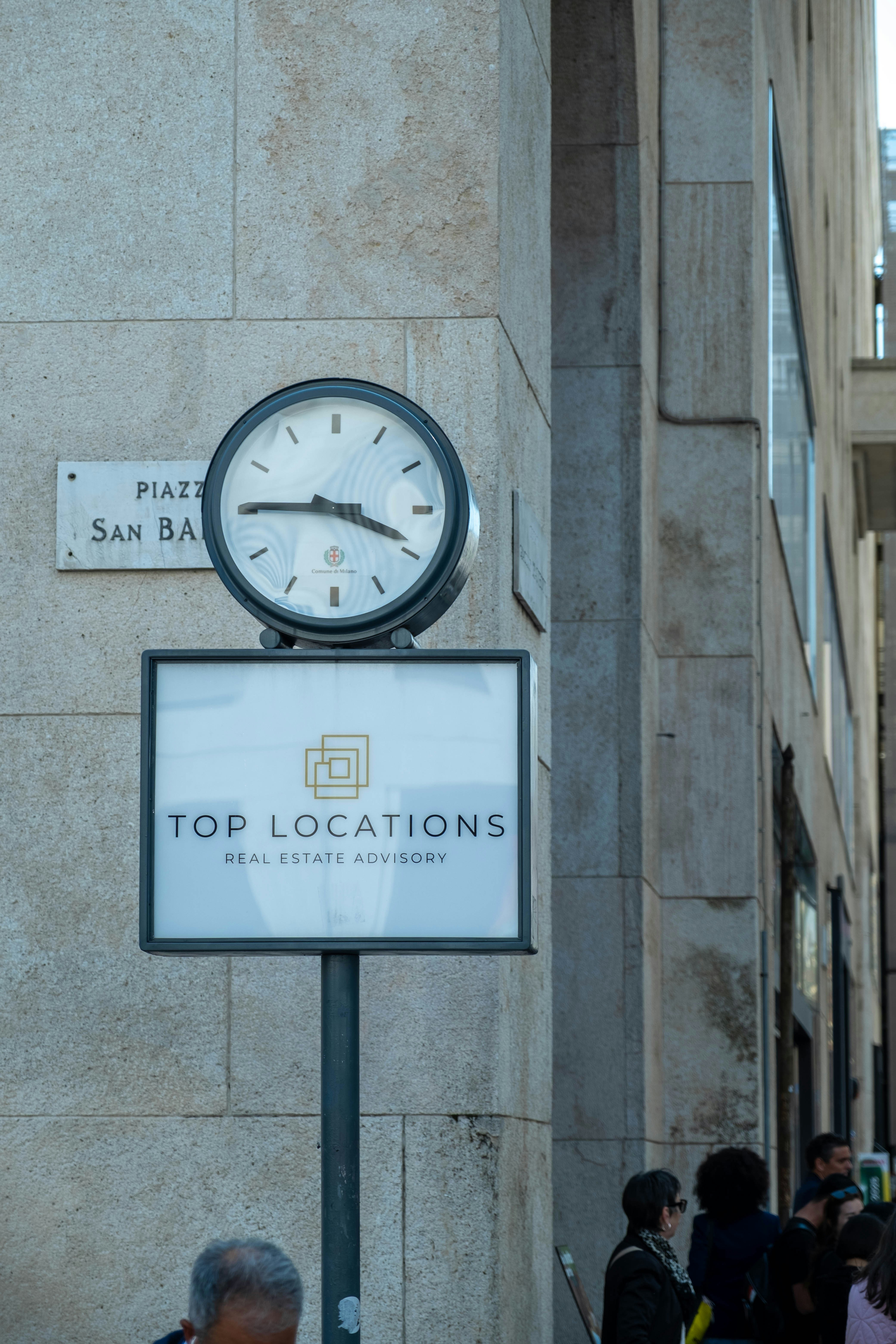 A clock and real estate sign stand outside.
