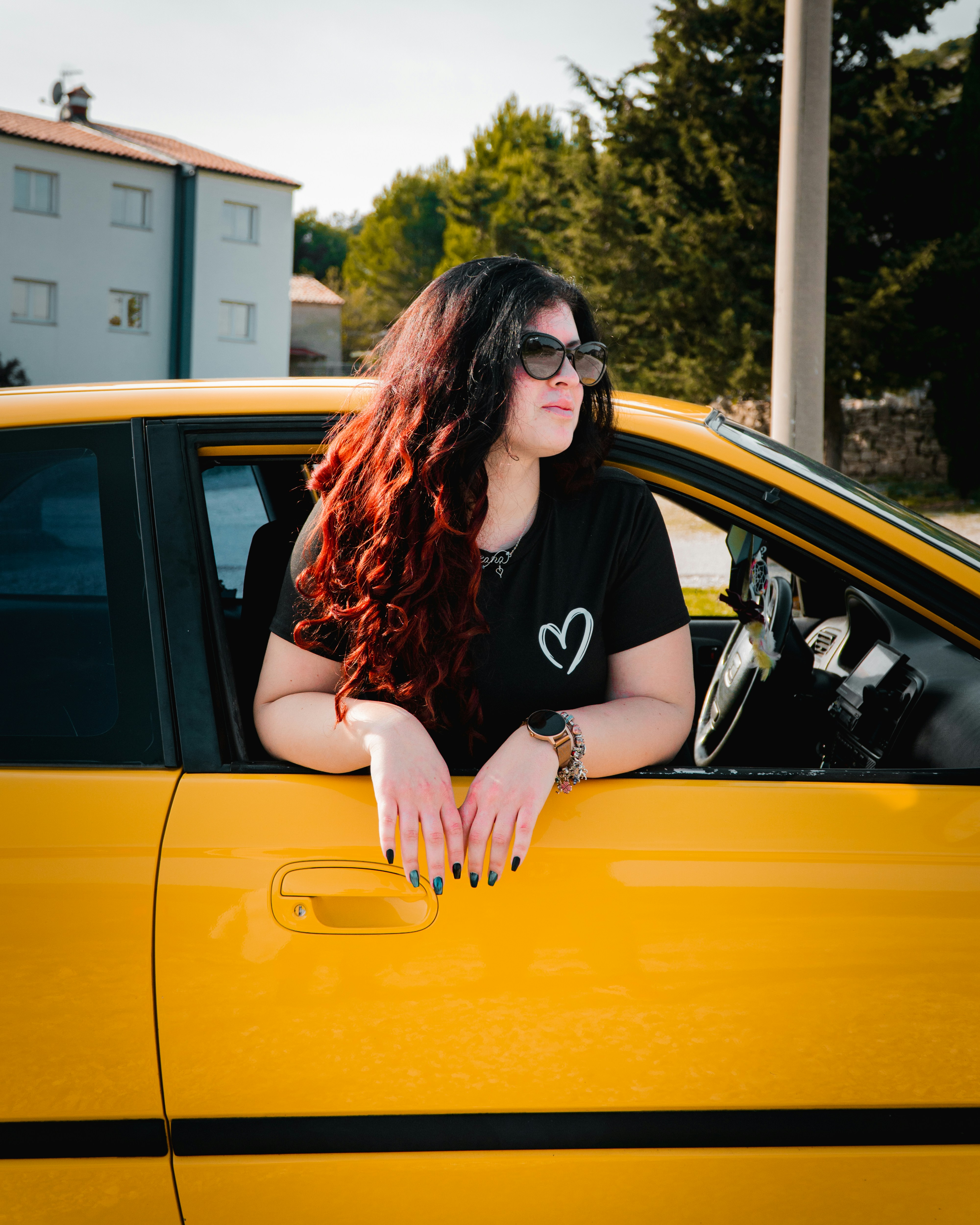 Woman with long hair looks out of a yellow car.