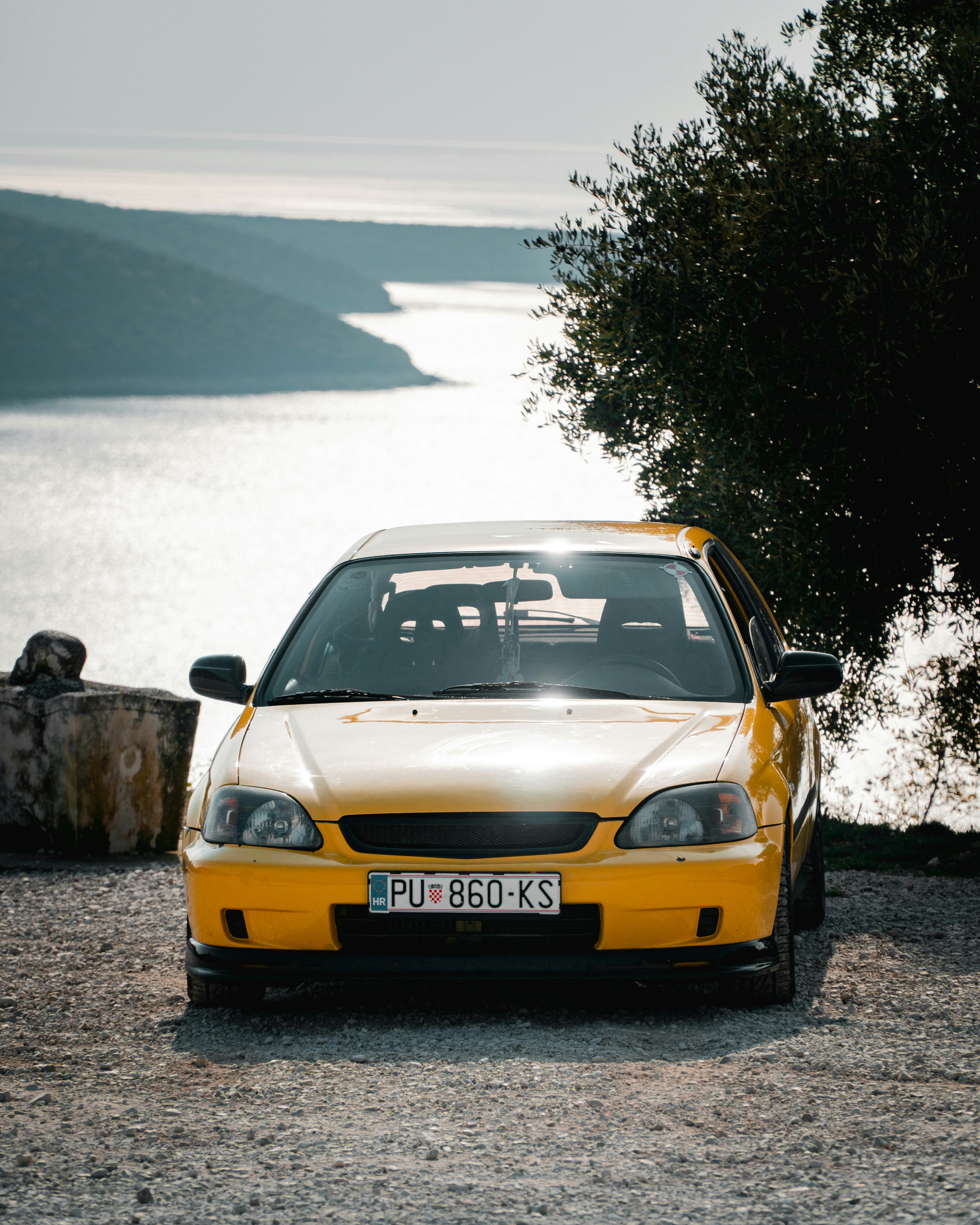 A yellow car is parked near water.