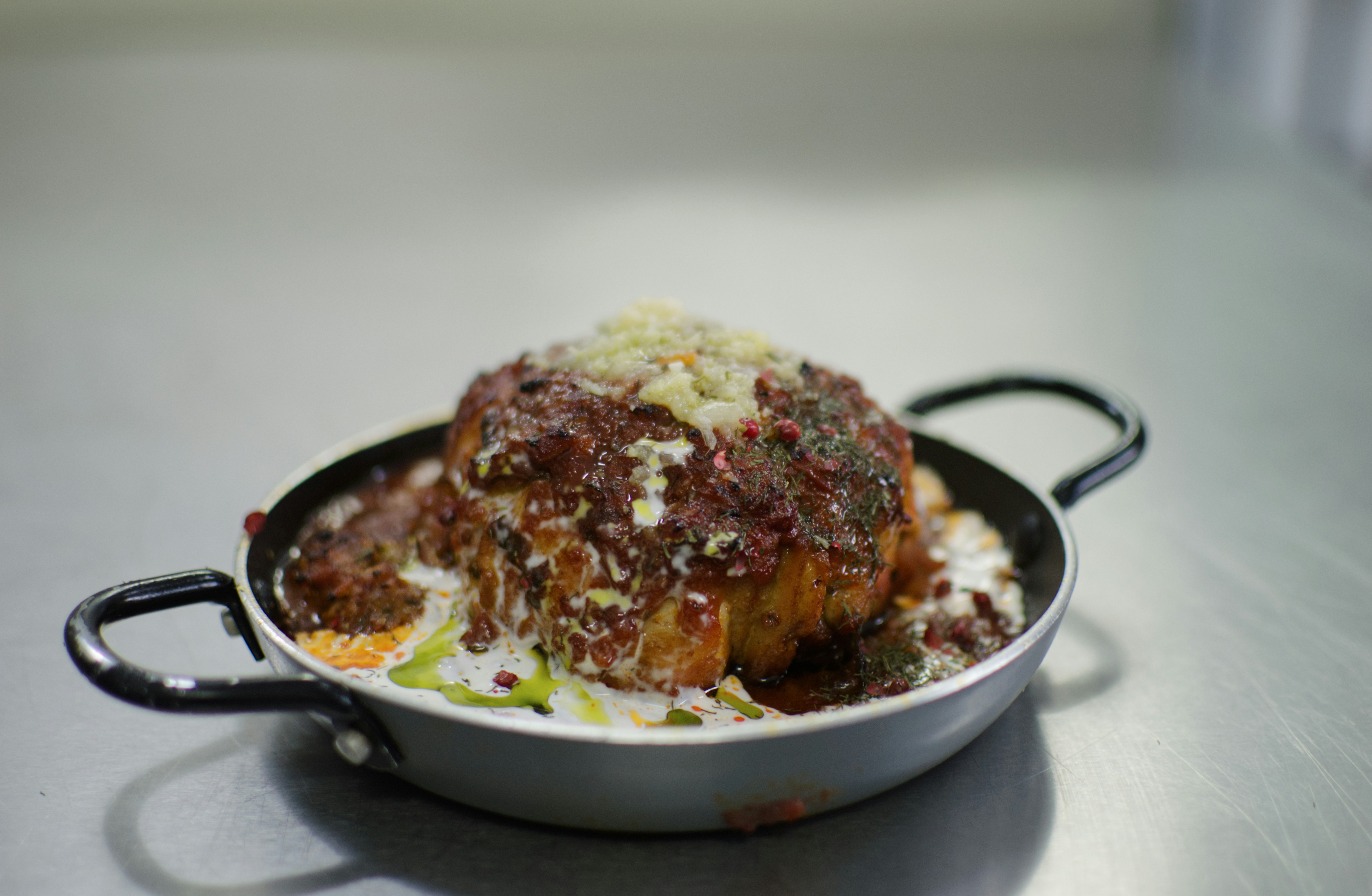 A gourmet dish sits inside a small, metal pan.