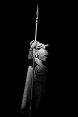A statue of a warrior stands holding a spear.