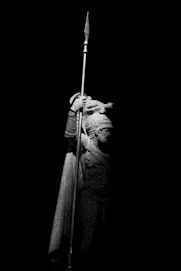 A statue of a warrior stands holding a spear.